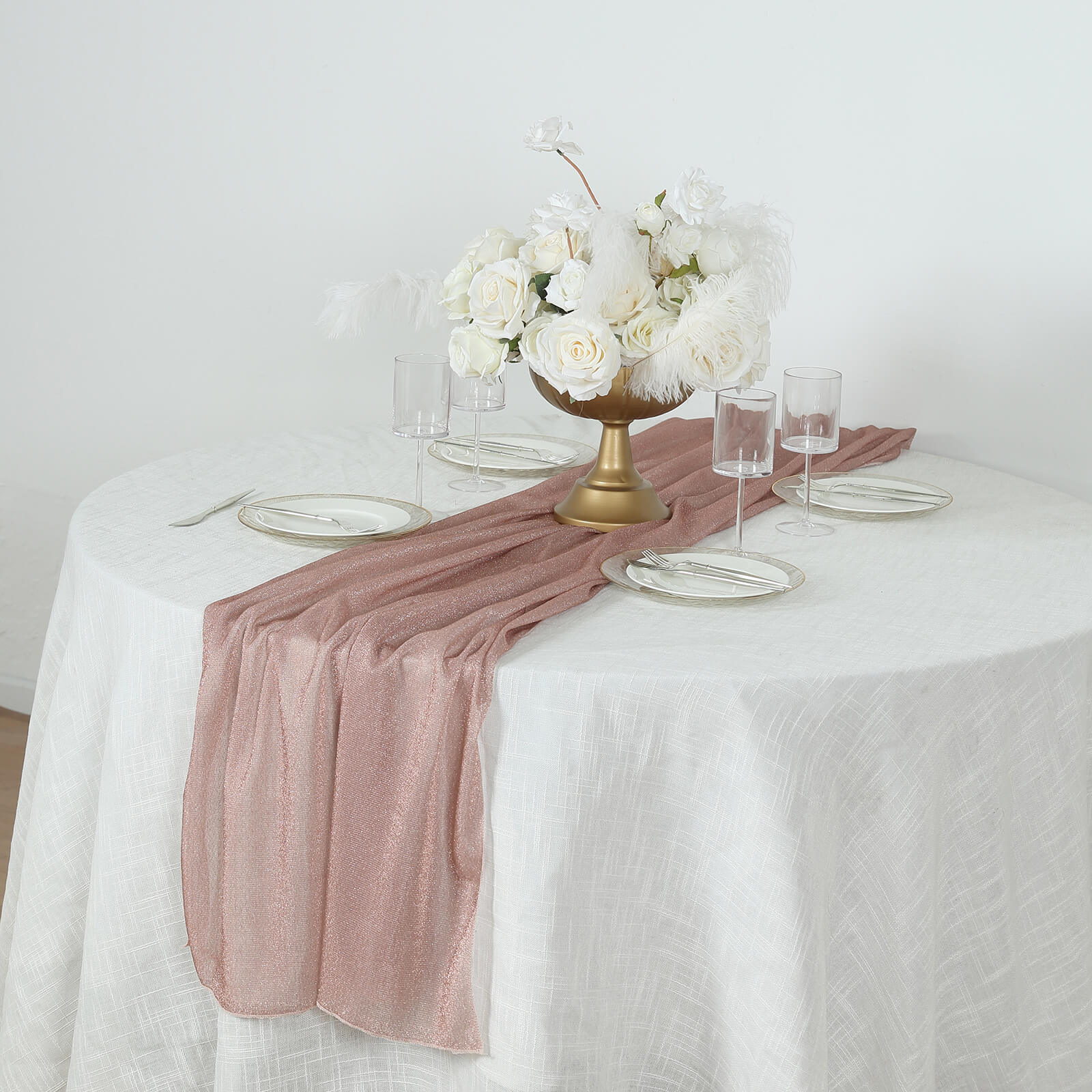 Rose gold sparkling glitter table runner on a white table with flowers.