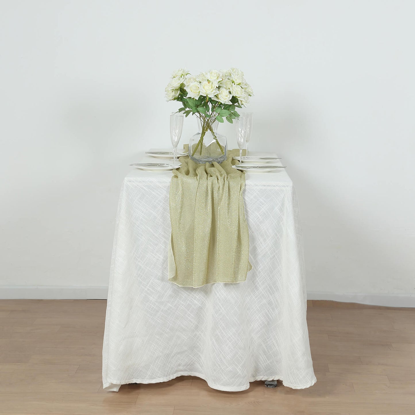 Champagne glitter gauze table runner on a white table with flowers.
