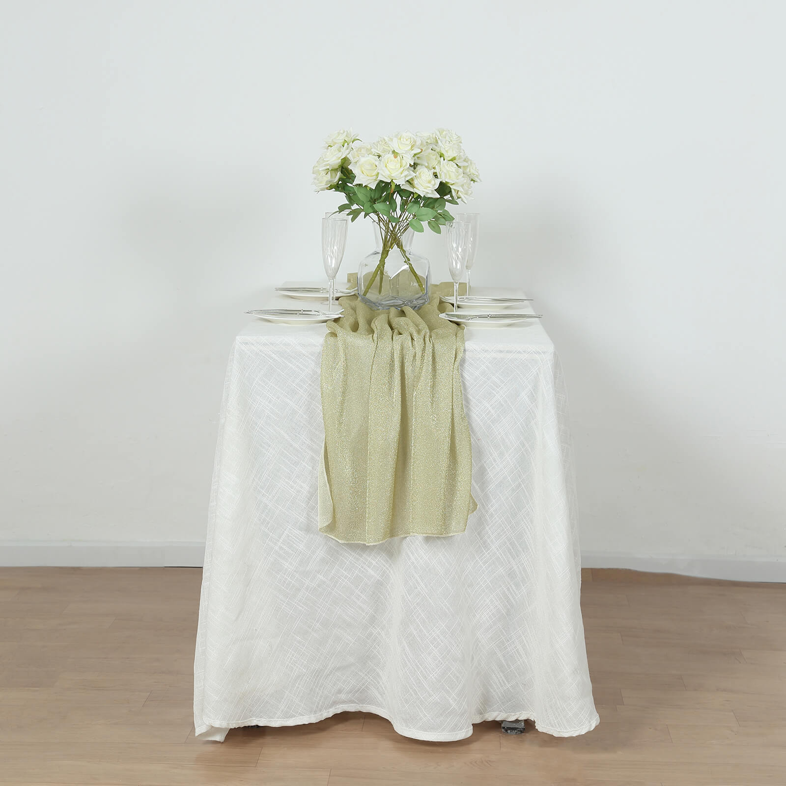 Champagne glitter gauze table runner on a white table with flowers.