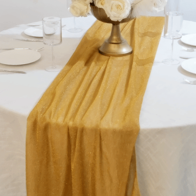 Gold sparkling glitter gauze table runner on a white table.