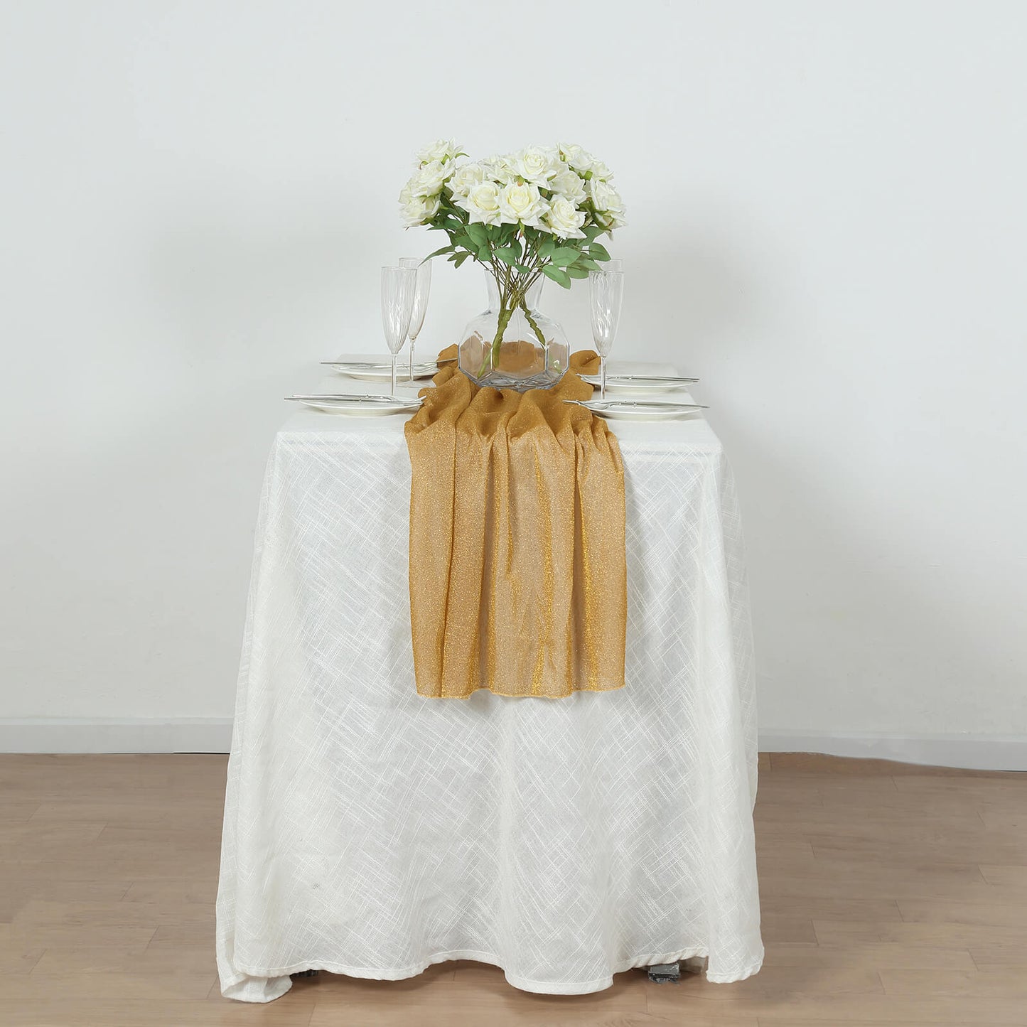 Gold sparkling glitter gauze table runner on a white table.