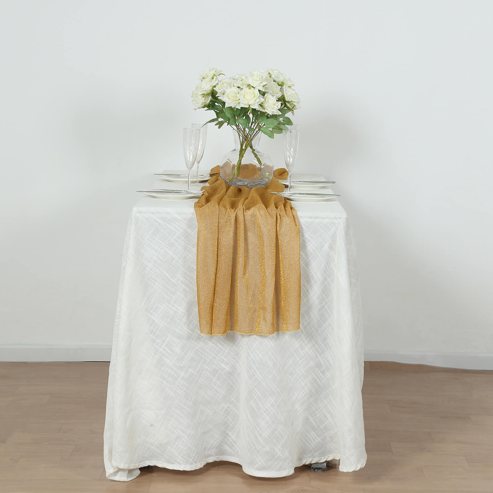 Gold sparkling glitter gauze table runner on a white table.