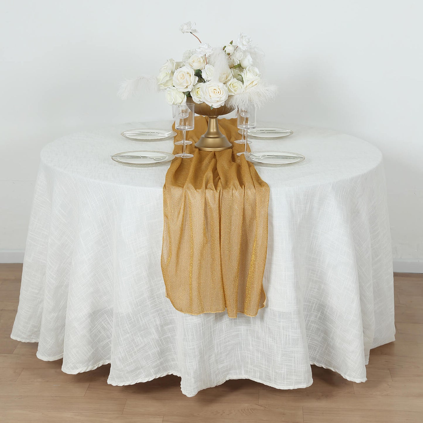 Gold sparkling glitter gauze table runner on a white table.