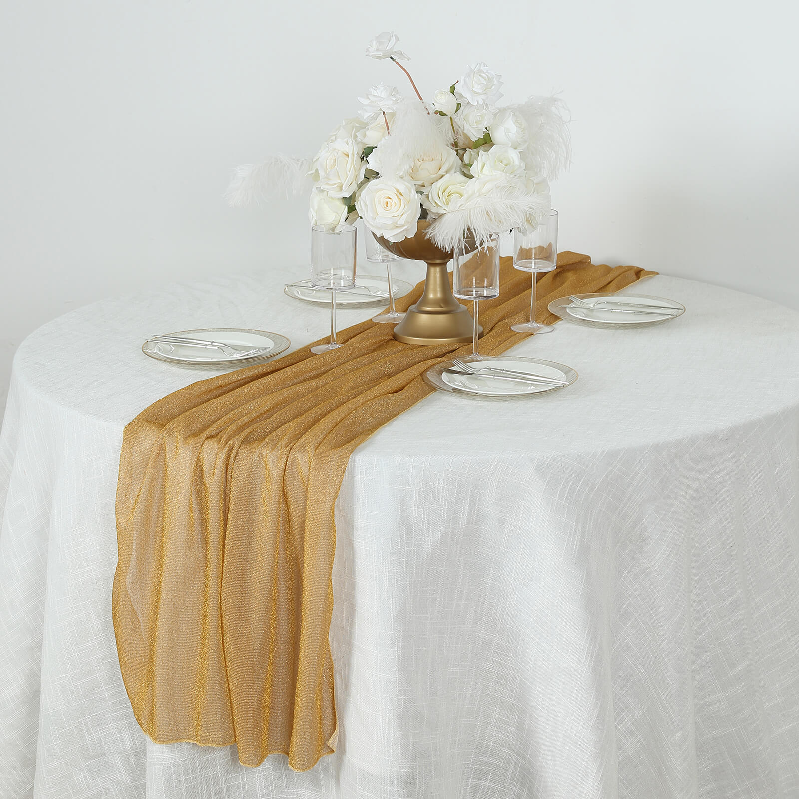Gold sparkling glitter table runner on a white table with floral centerpiece.