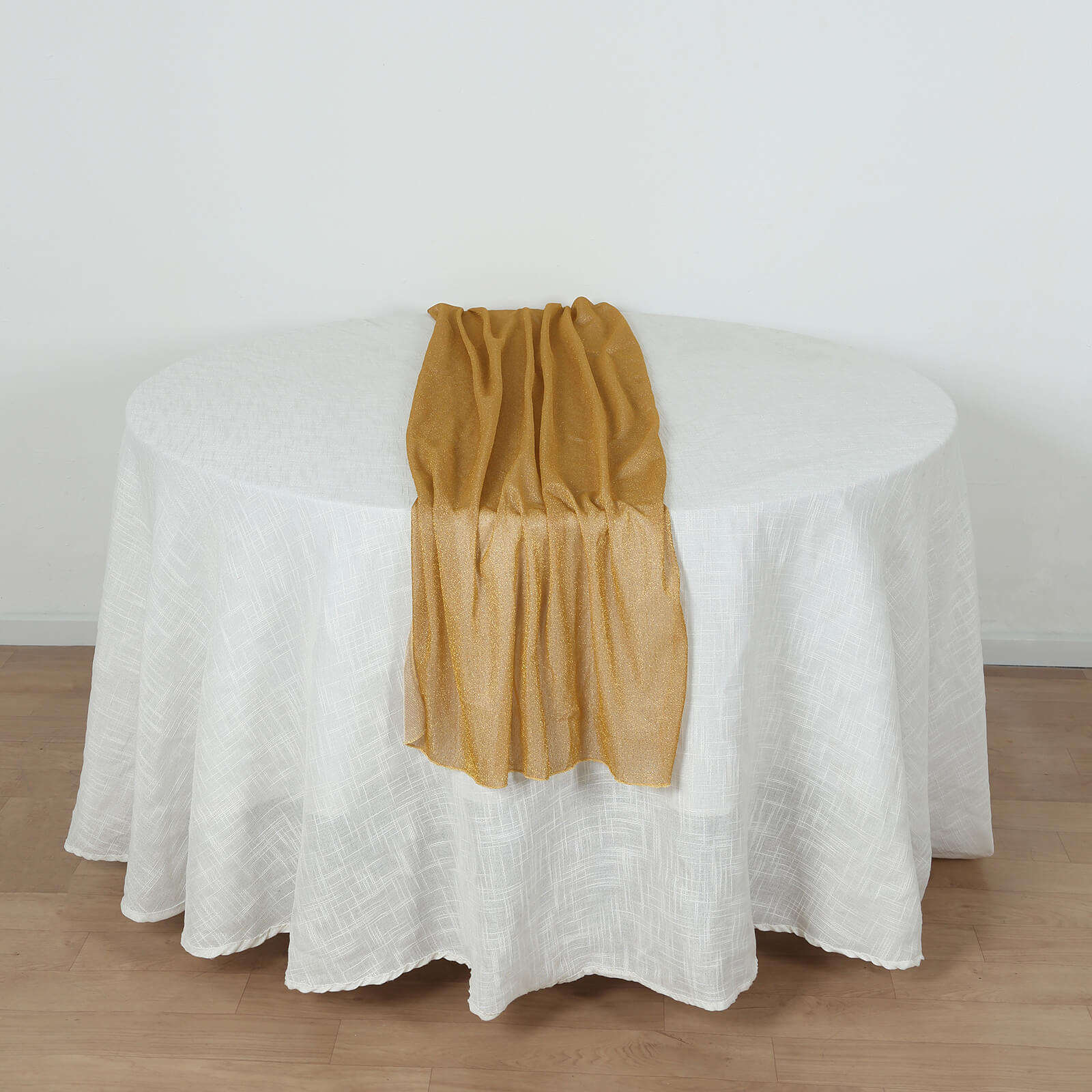 Gold sparkling glitter gauze table runner on a white table.