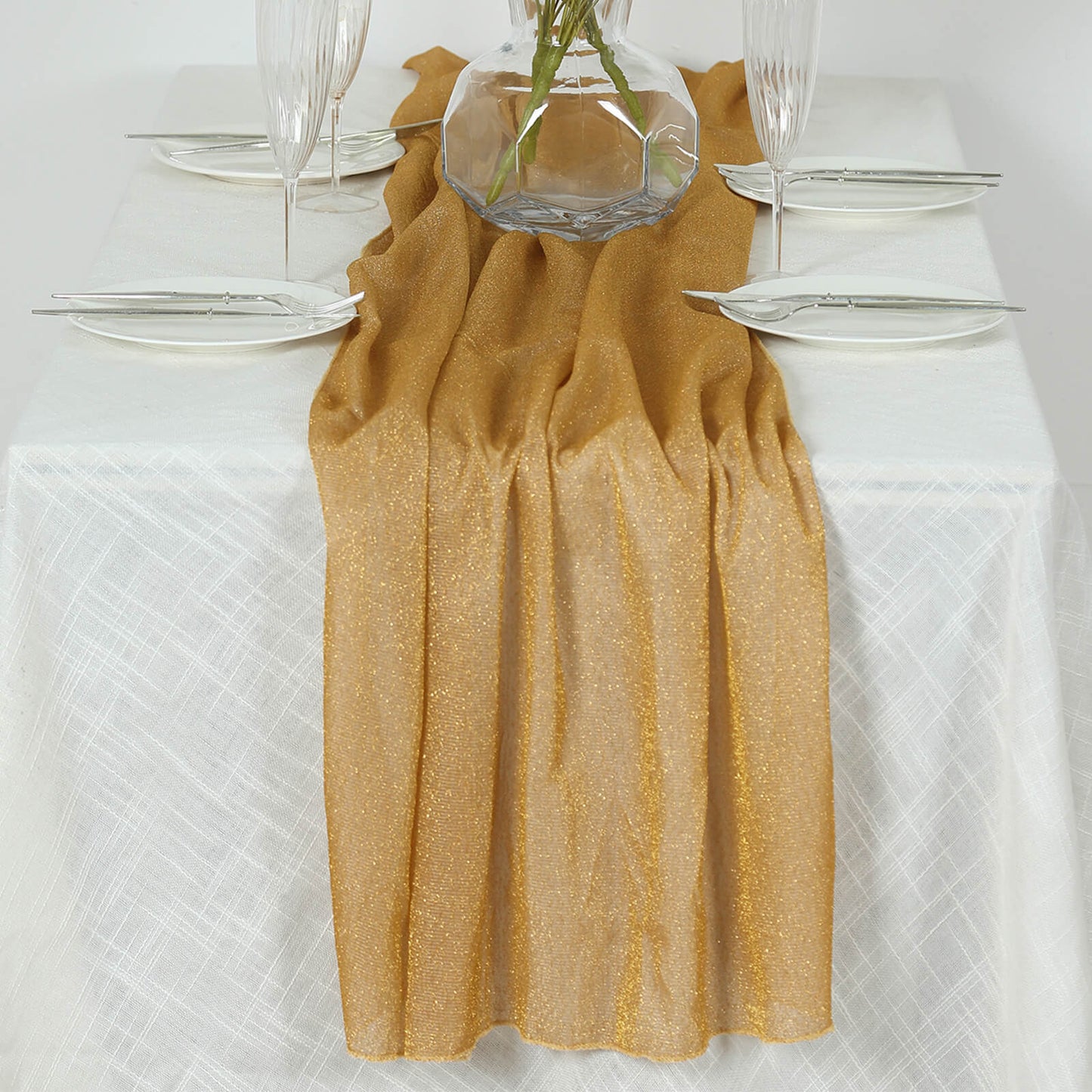 Gold sparkling glitter table runner on a white tablecloth.