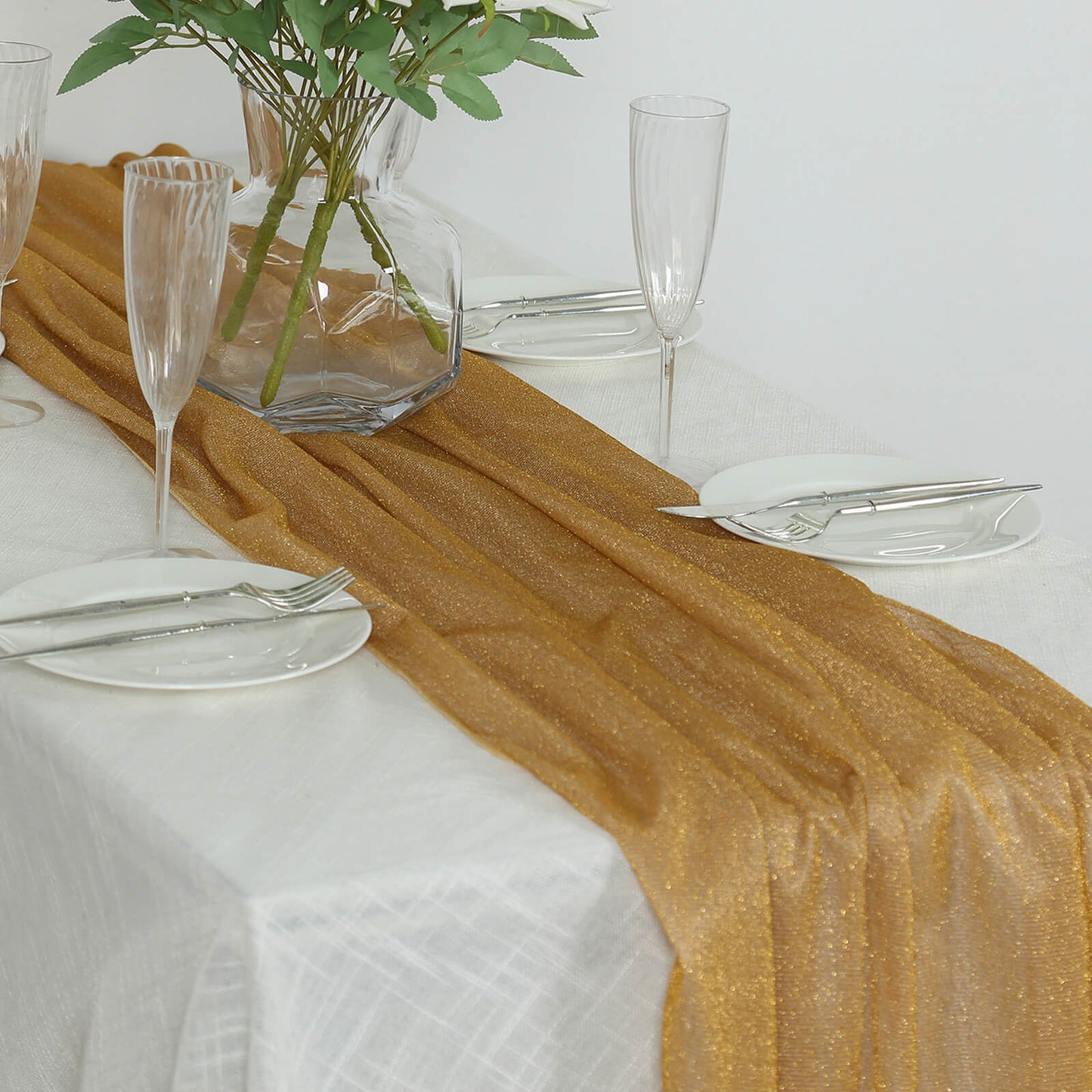 Gold sparkling glitter gauze table runner on a white table.
