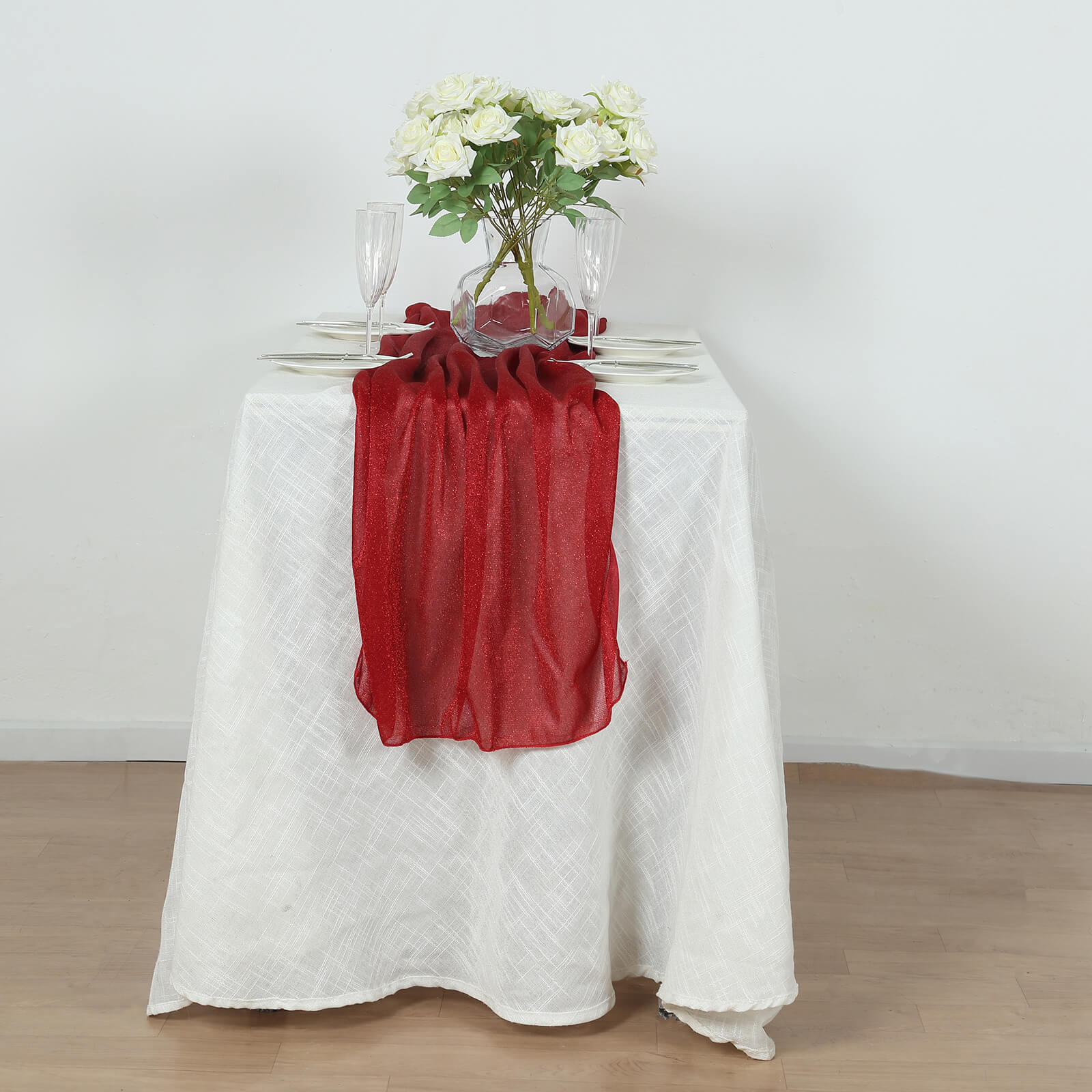 Red sparkling glitter gauze table runner on a white table.