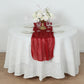 Red sparkling glitter gauze table runner on a white table with floral centerpiece.