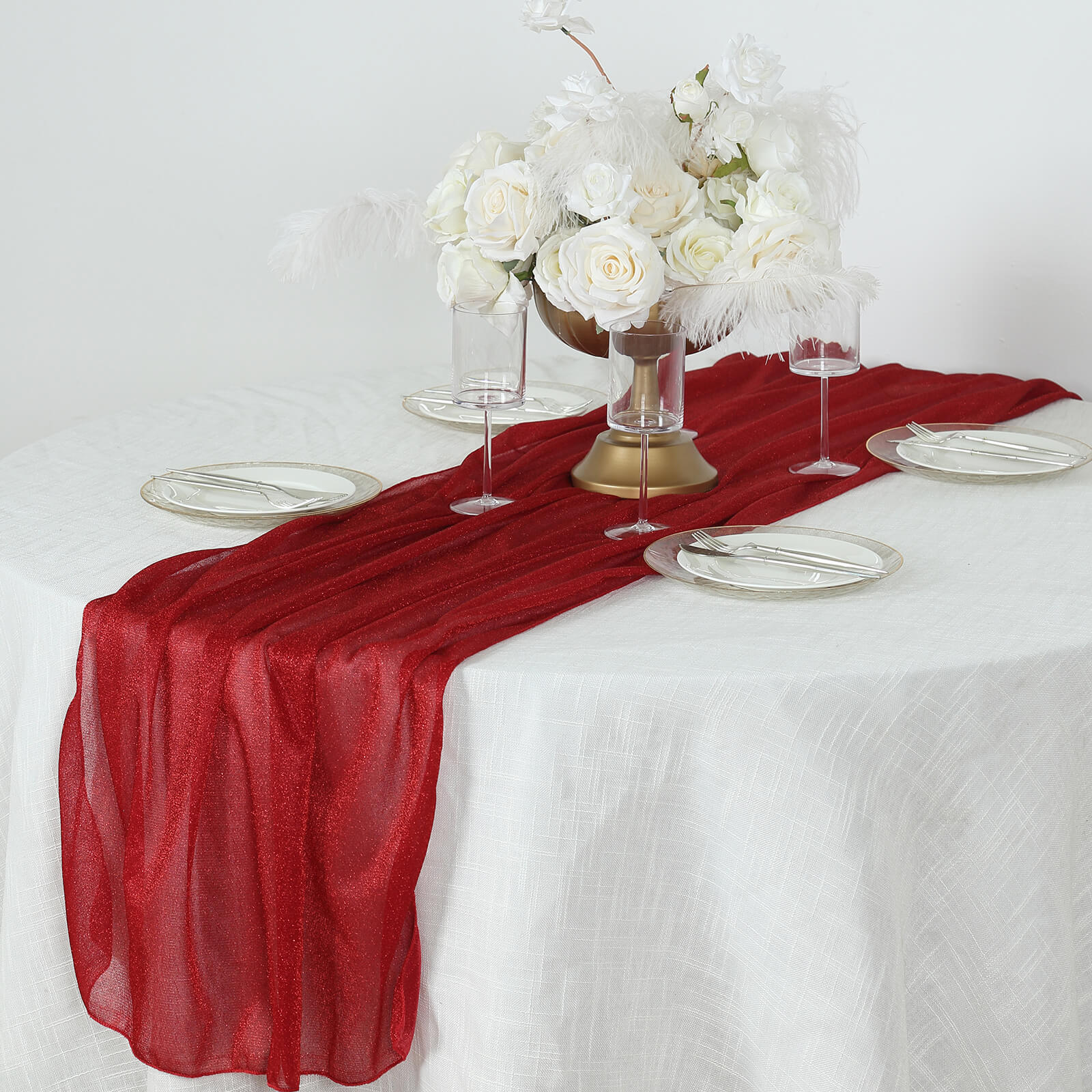 Red sparkling glitter gauze table runner on a white table.