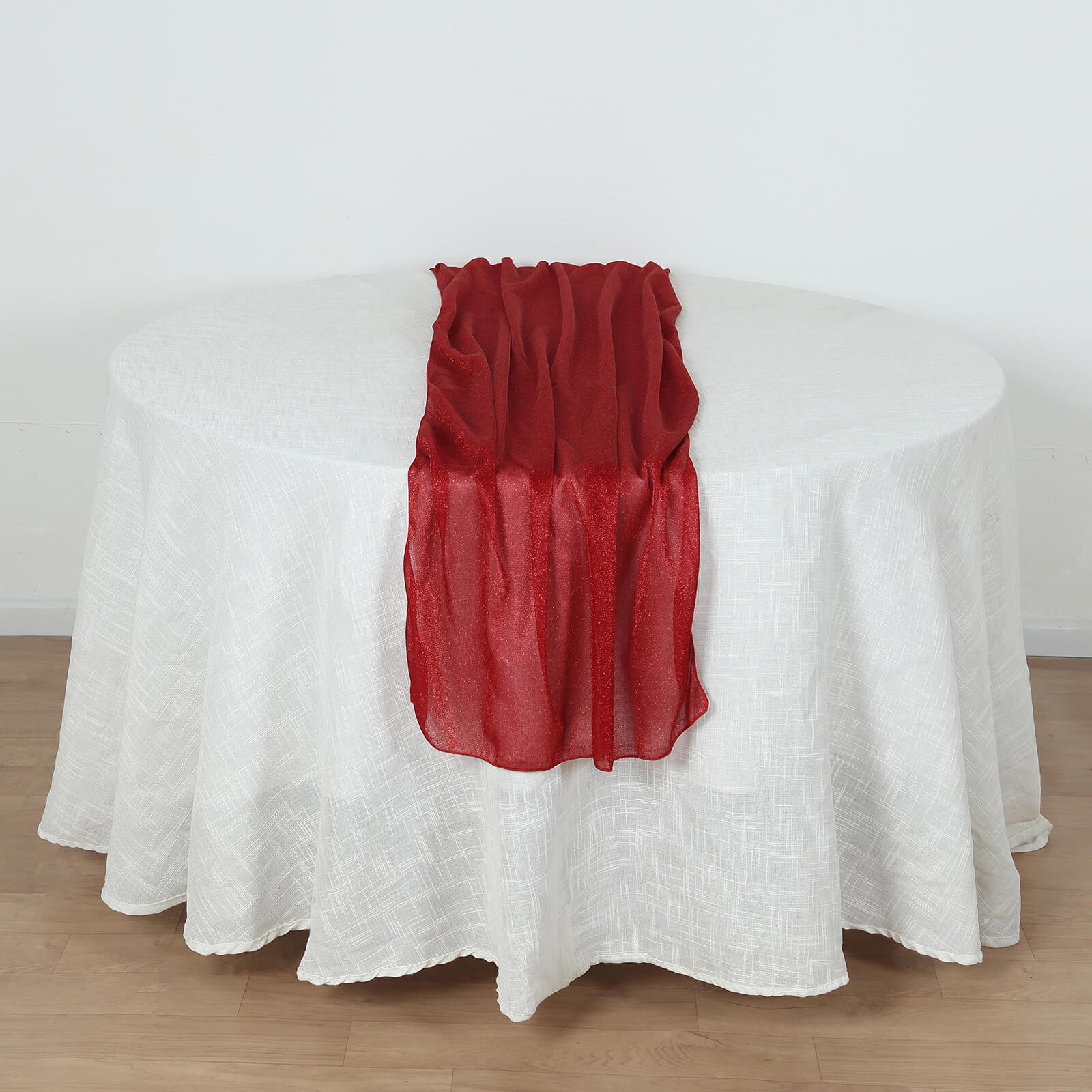 Red sparkling glitter gauze table runner on a white table.