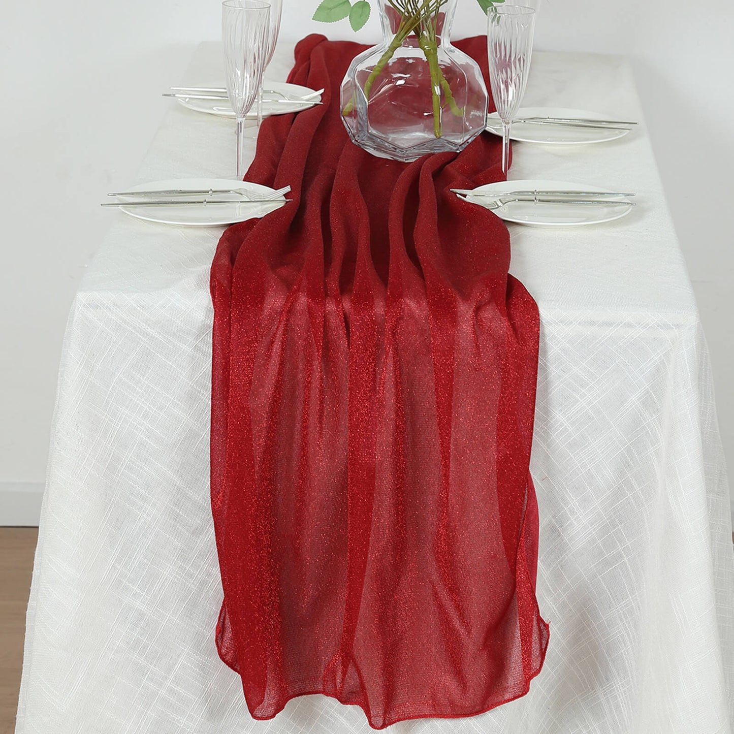 Red sparkling glitter gauze table runner on a white table.