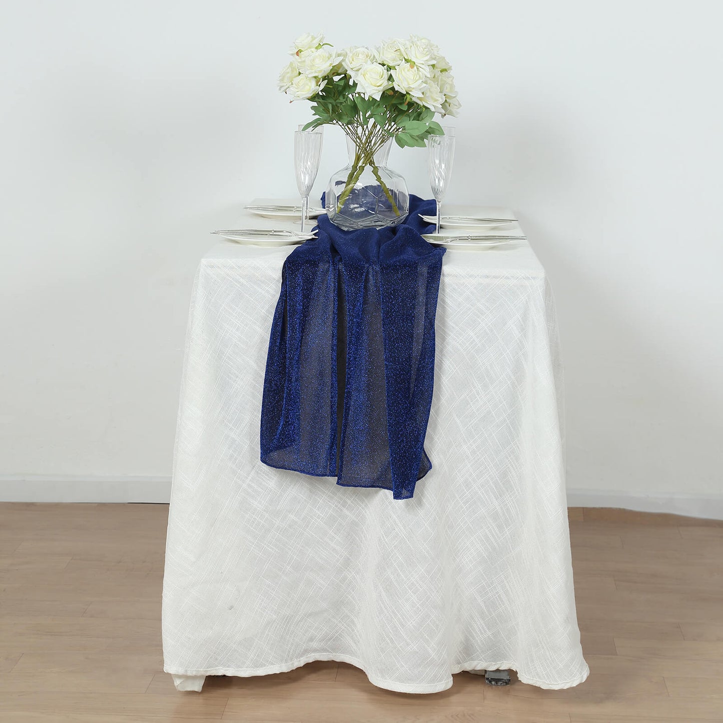 Royal blue sparkling glitter gauze table runner on a white table.