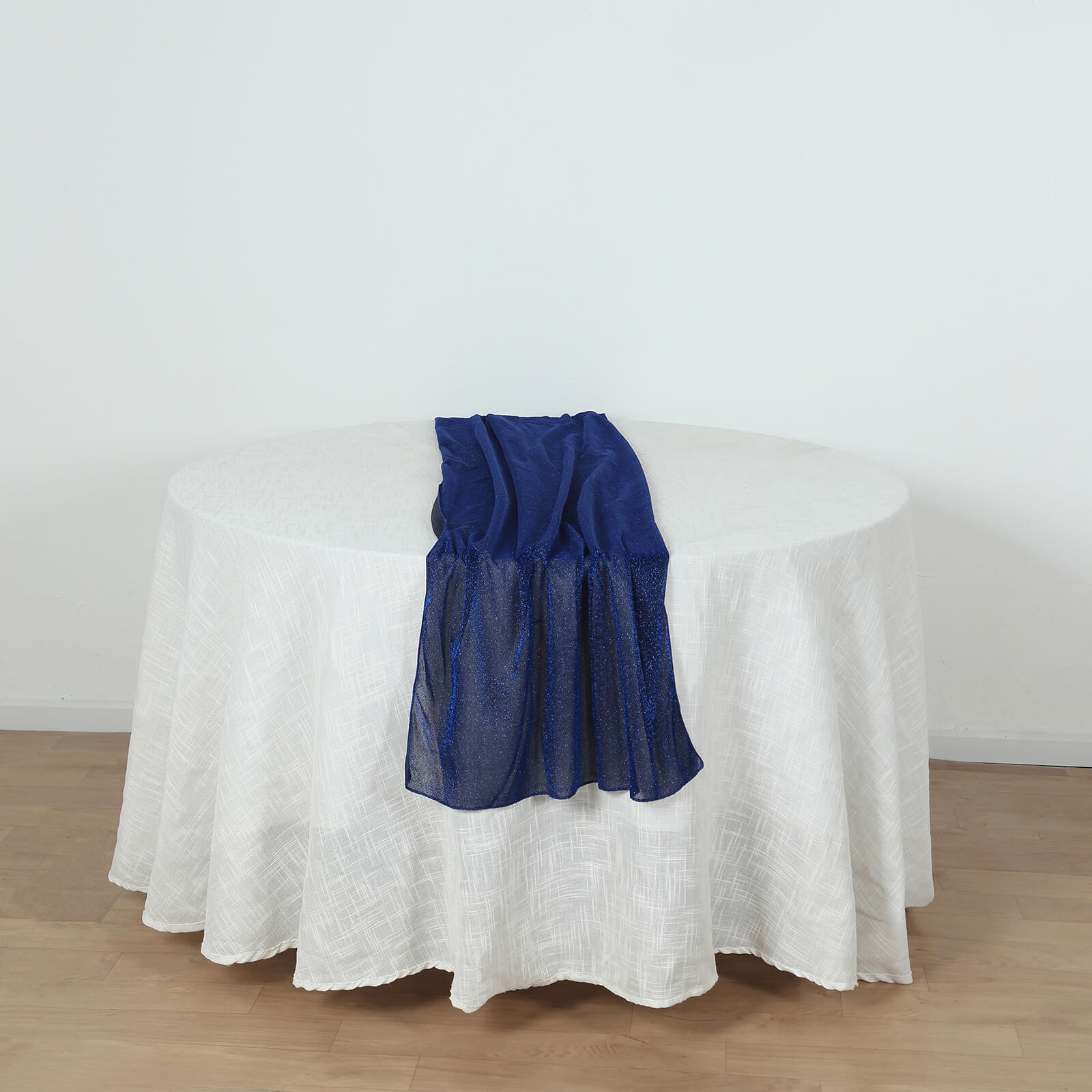 Royal blue sparkling glitter gauze table runner on a white table.