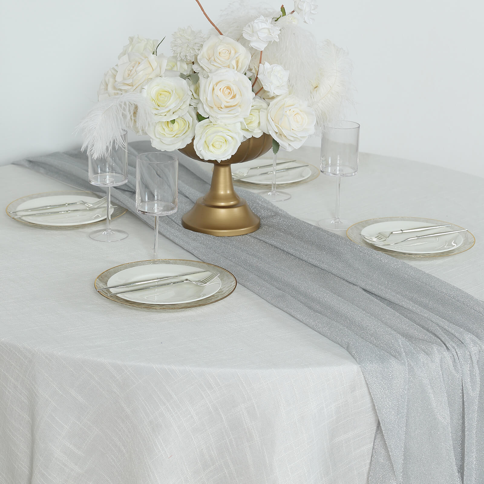 Silver glitter gauze table runner on a table with floral centerpiece and glassware.