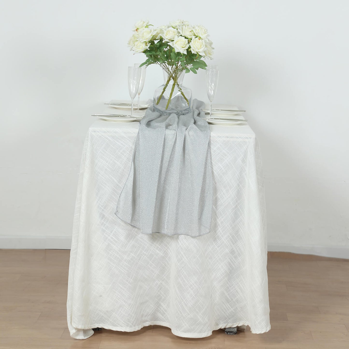 Silver sparkling glitter gauze table runner on a white table.