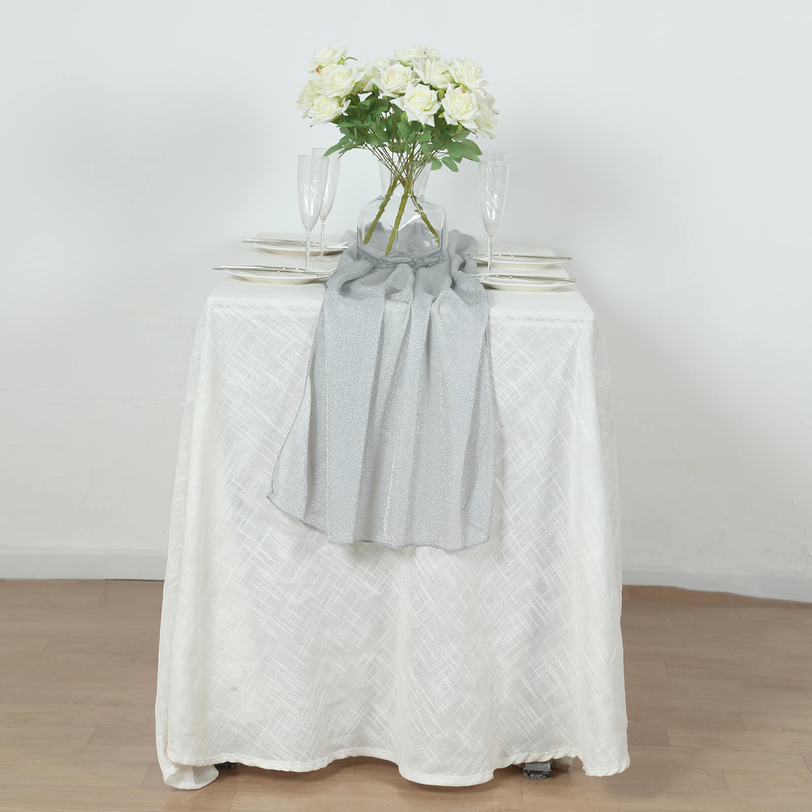 Silver sparkling glitter gauze table runner on a white table.