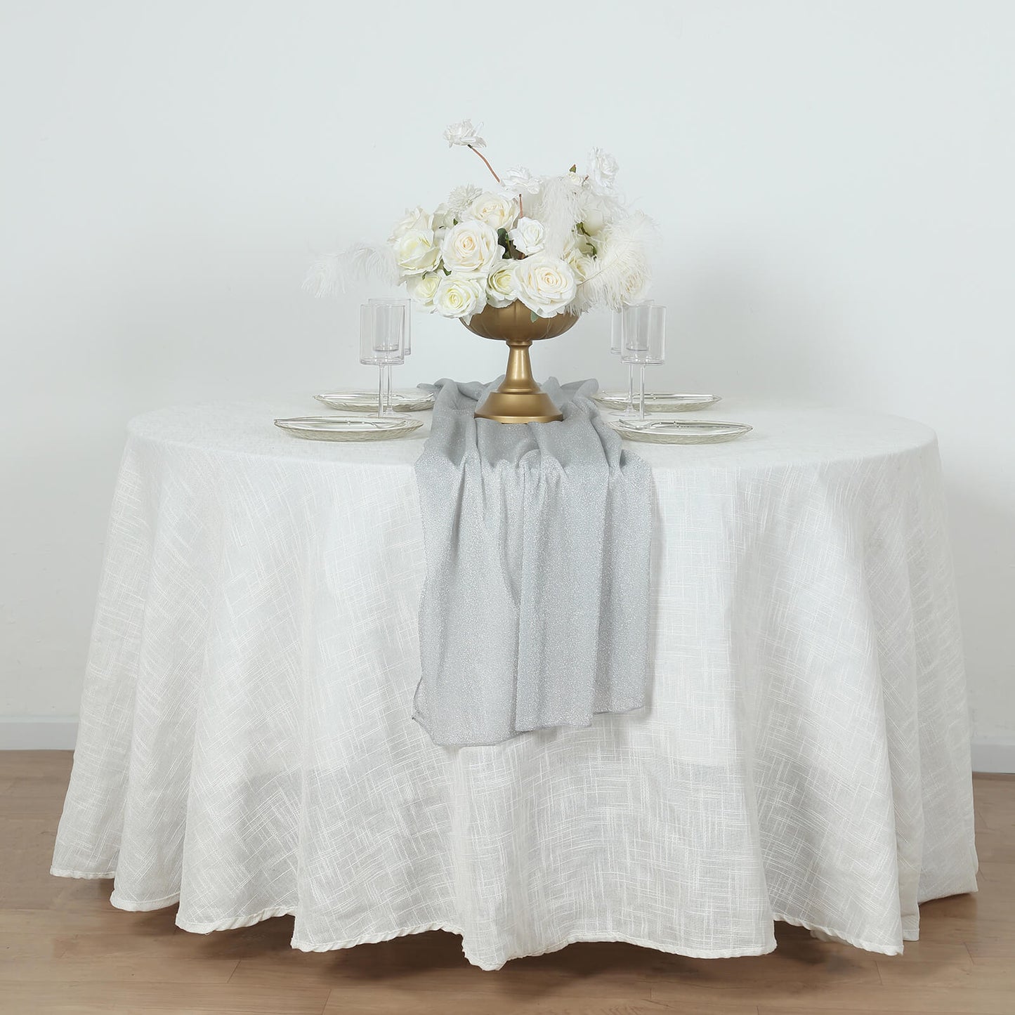 Silver sparkling glitter gauze table runner on a white table.