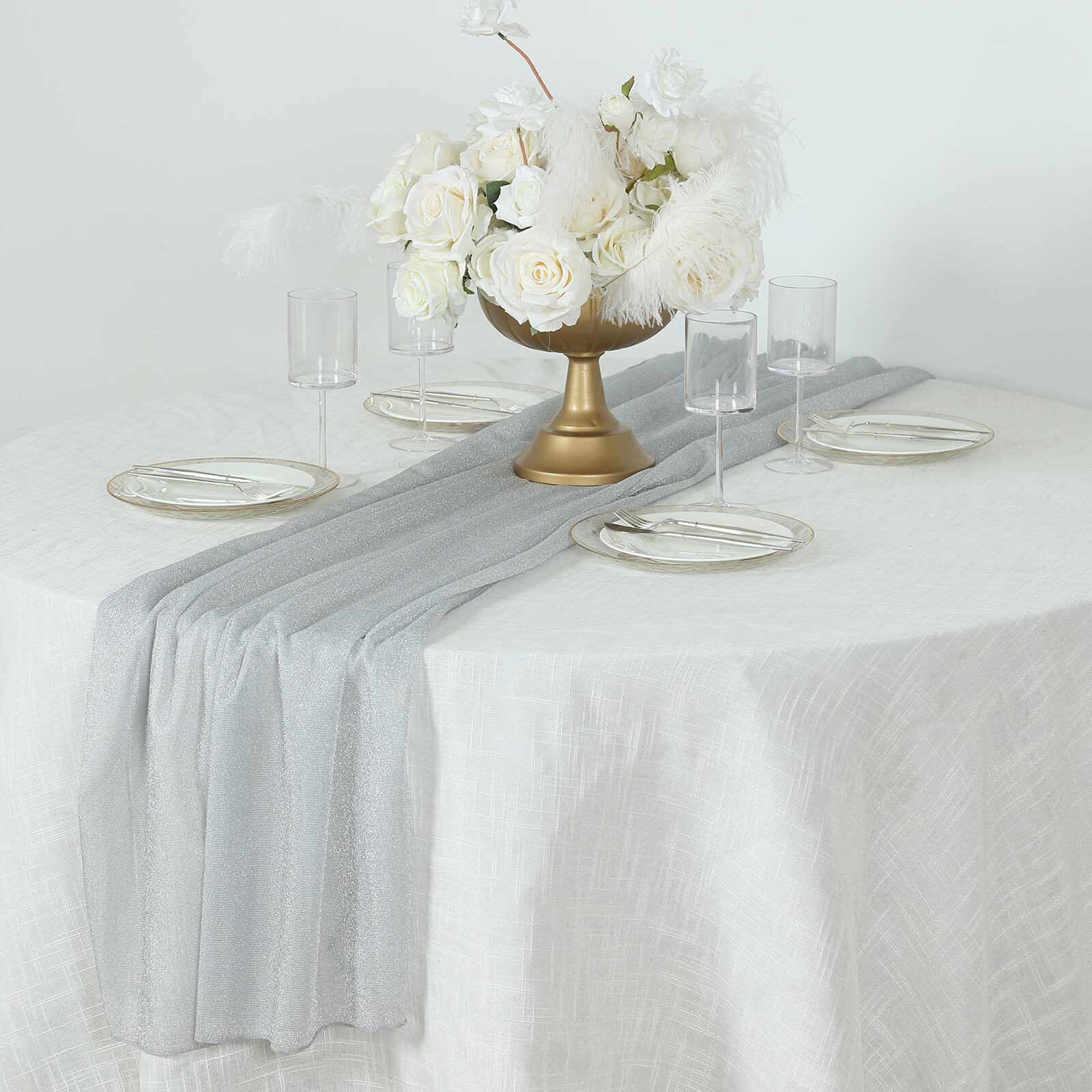 Silver sparkling glitter gauze table runner on a white table setting.