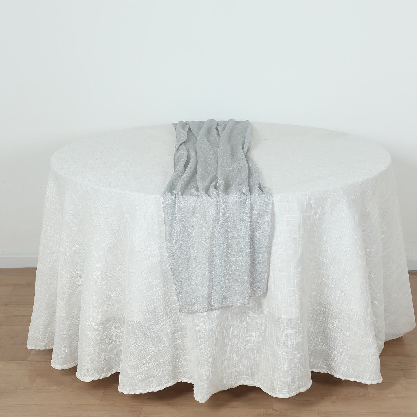 Silver sparkling glitter table runner on a white tablecloth.