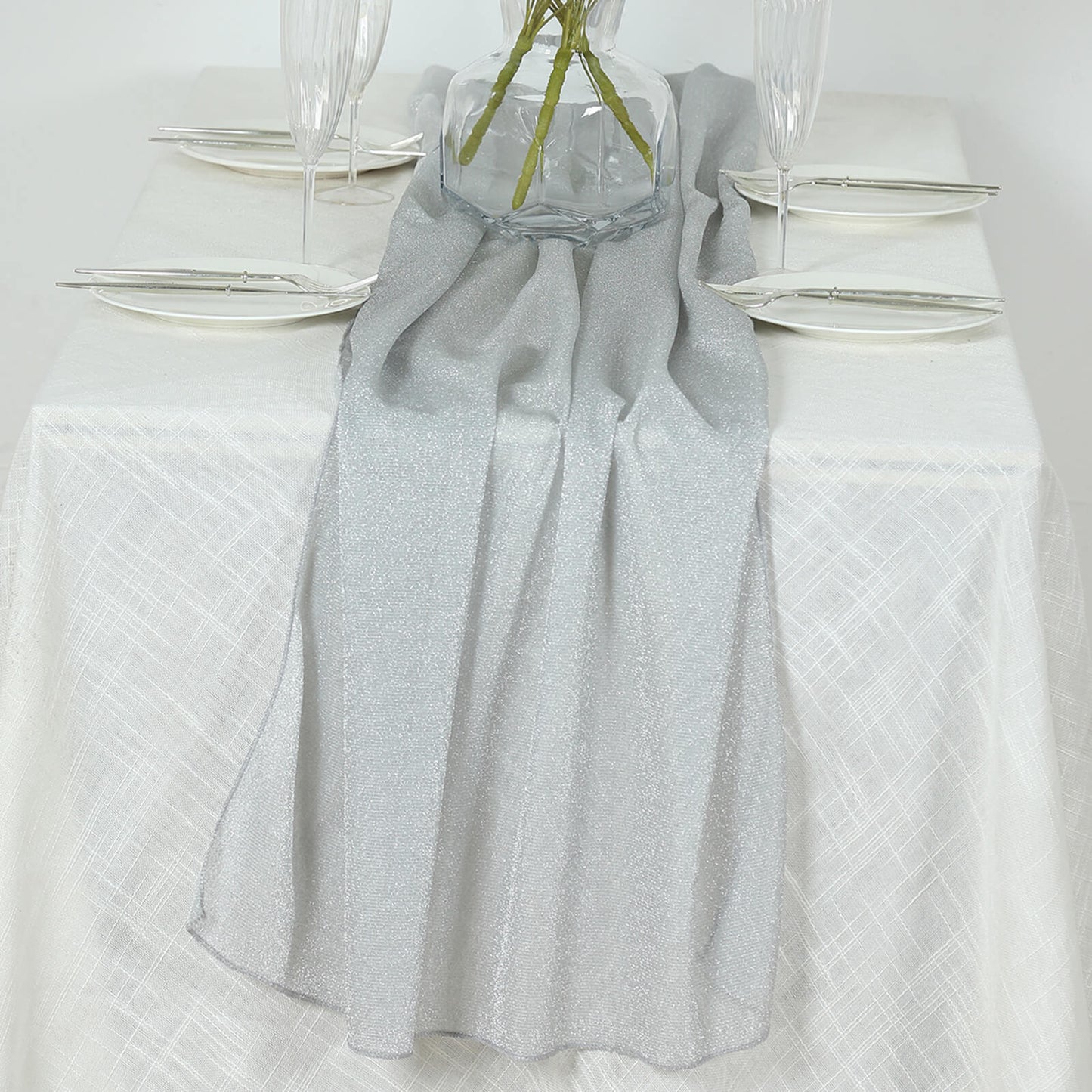 Silver sparkling glitter gauze table runner on a white table.