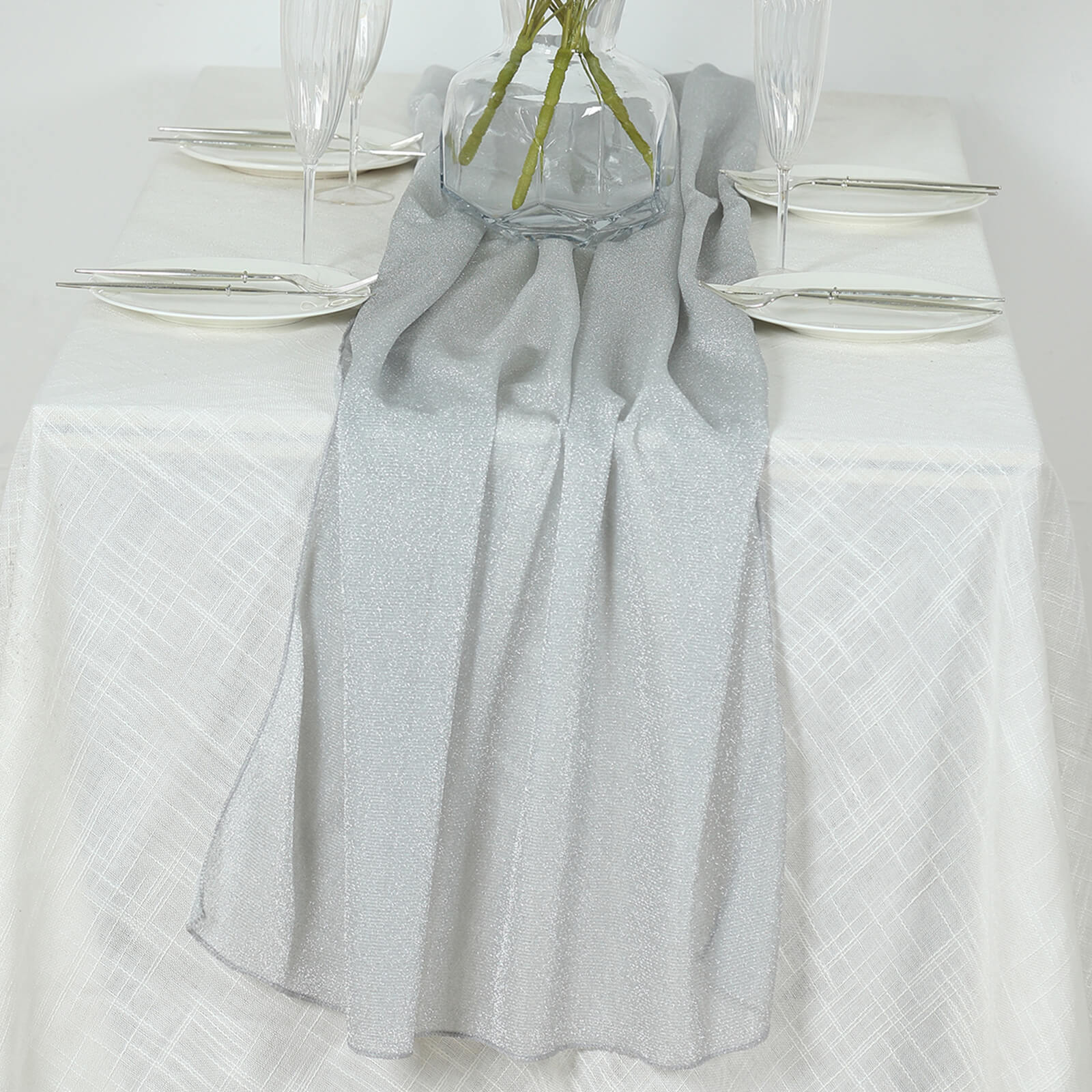 Silver sparkling glitter gauze table runner on a white table.