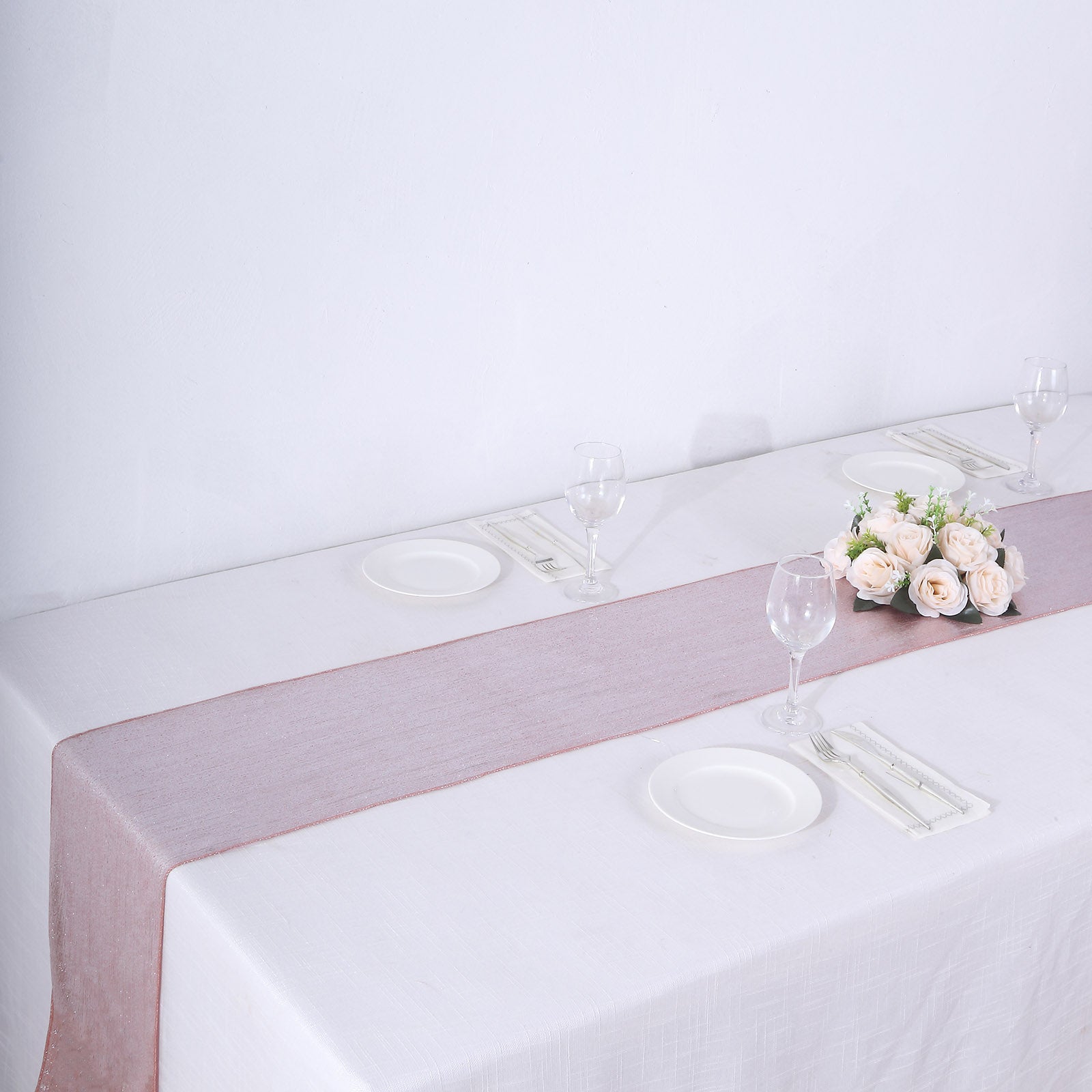 Rose gold shimmer sequin table runner on a white table setting.
