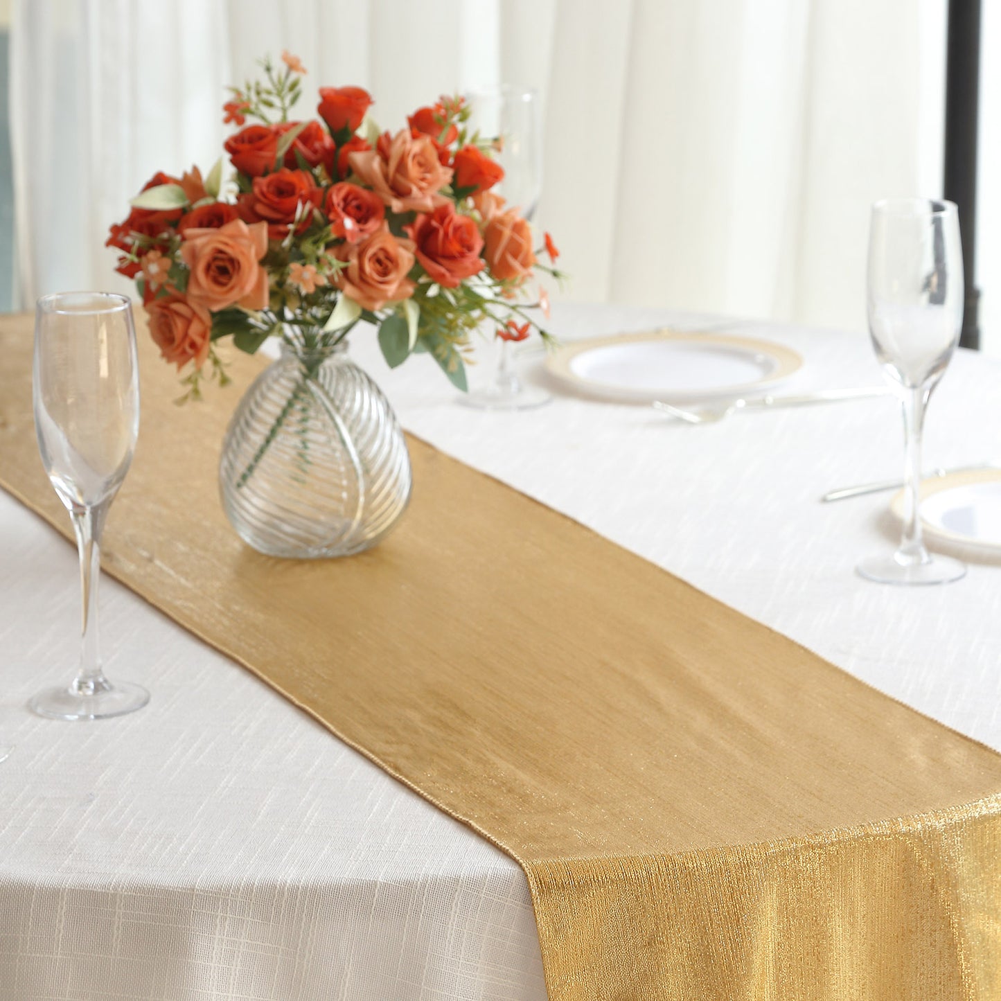 Gold shimmer sequin table runner on a white table with flowers.