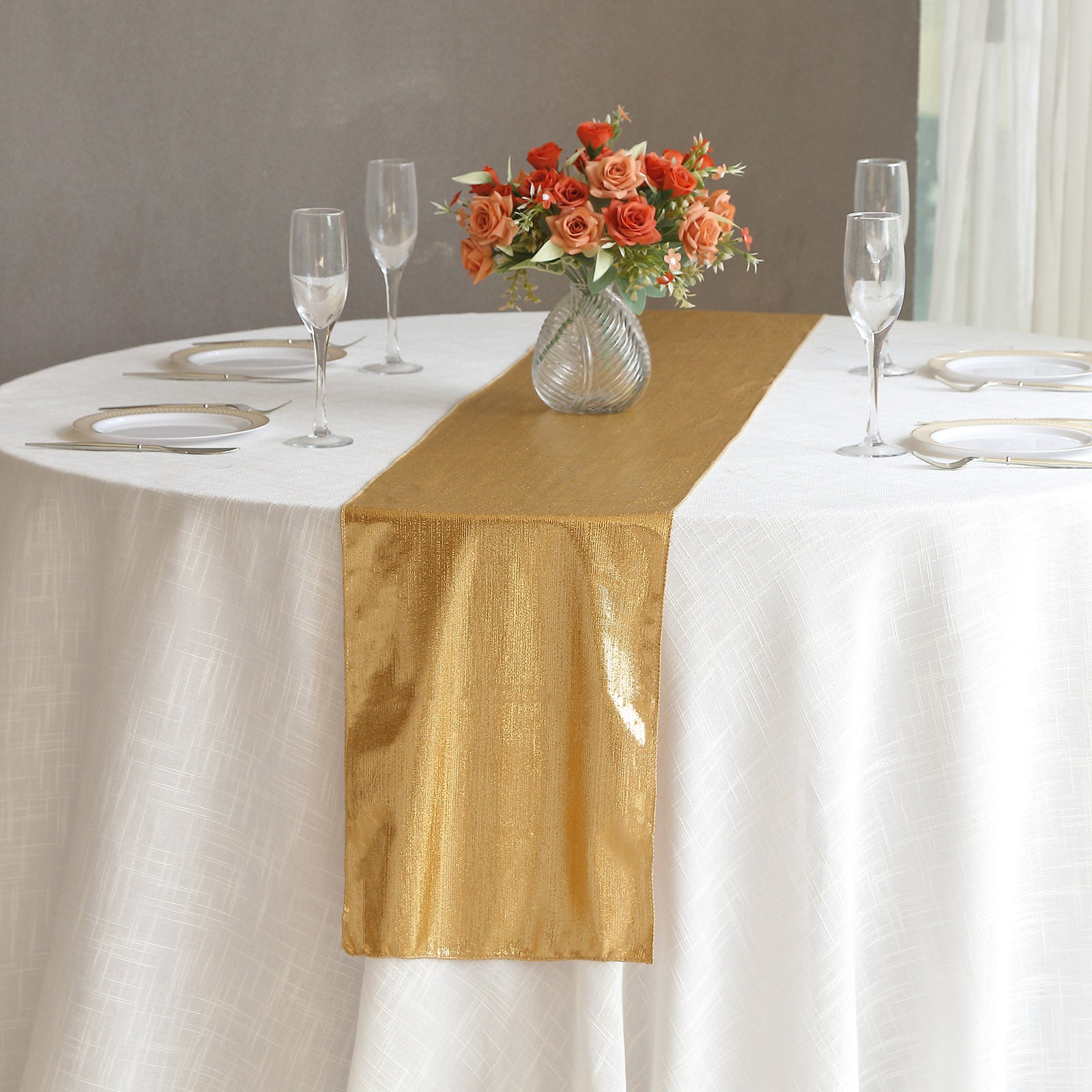 Gold shimmer sequin table runner on a white table with floral centerpiece.