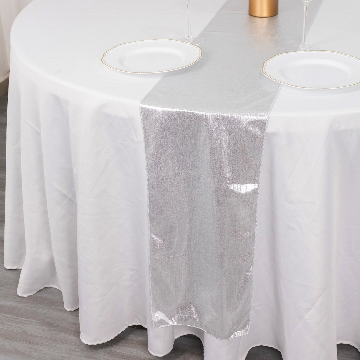 Silver shimmer sequin table runner on a round white table.
