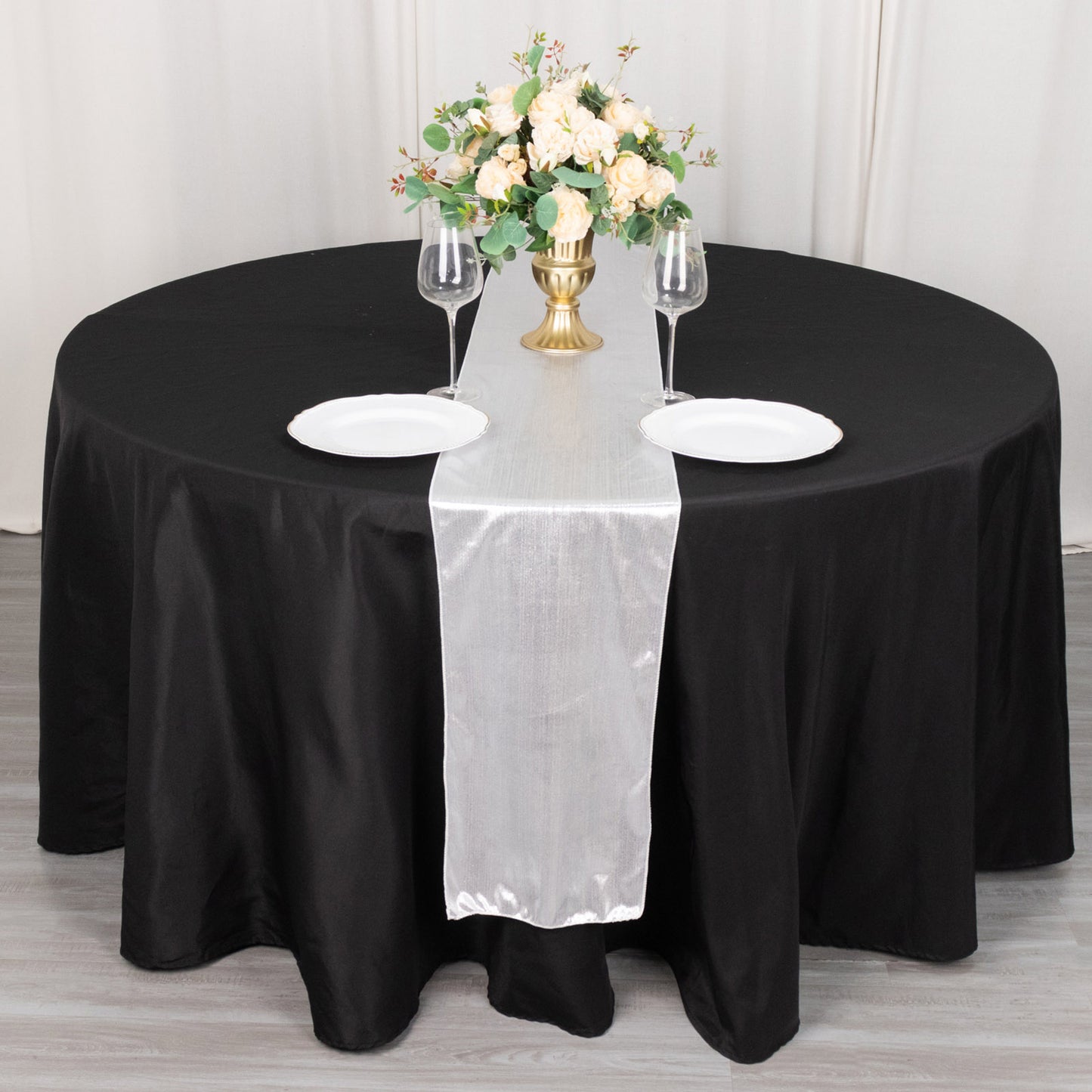 Silver shimmer sequin table runner on a black table setting.