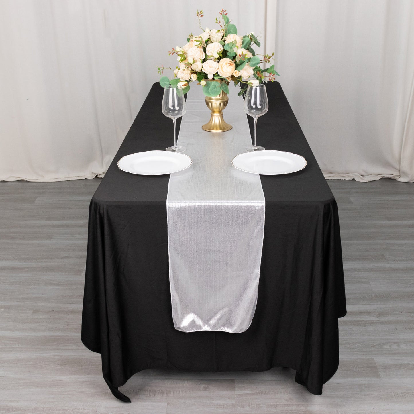 Silver shimmer sequin dots table runner on a black table with floral centerpiece.