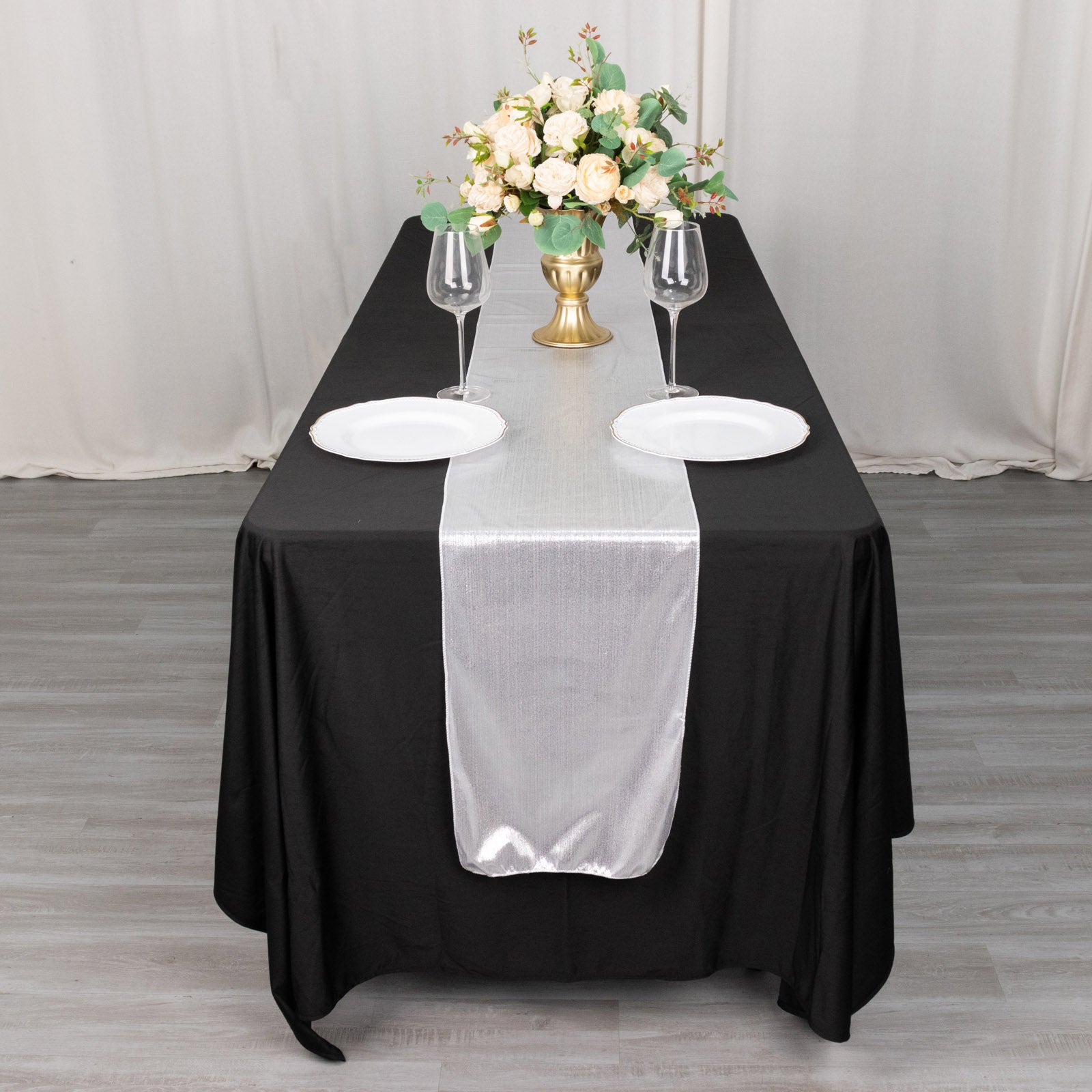 Silver shimmer sequin dots table runner on a black table with floral centerpiece.