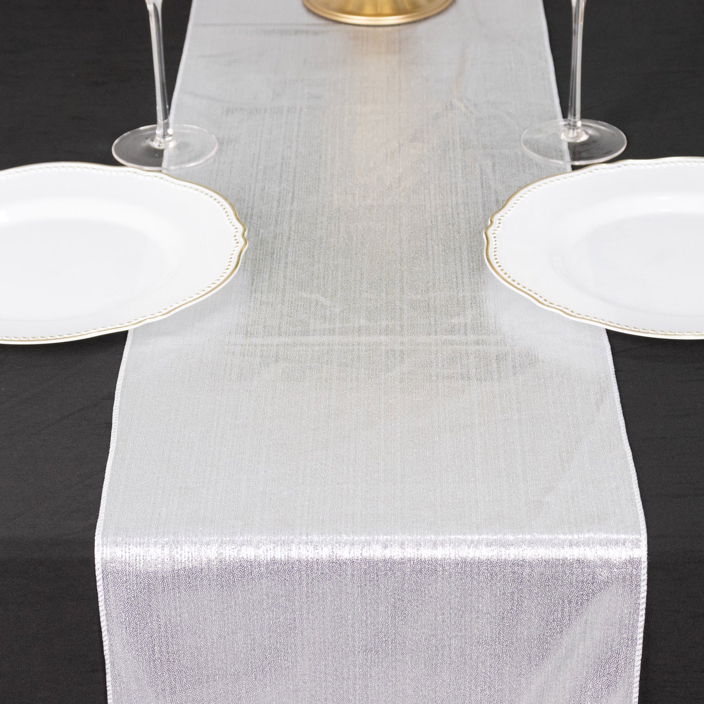Silver shimmer sequin table runner on a black table setting.