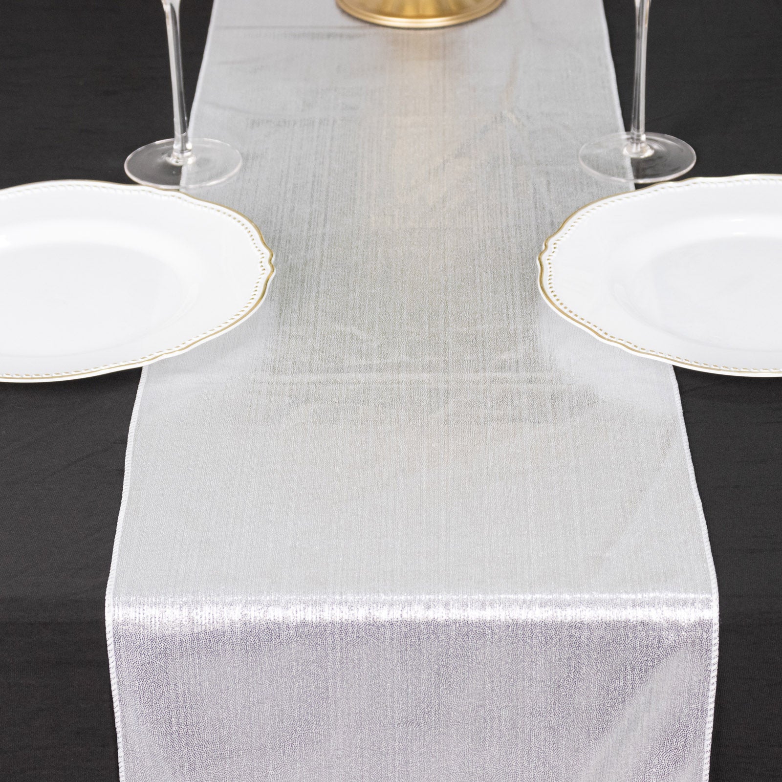 Silver shimmer sequin table runner on a black table setting.