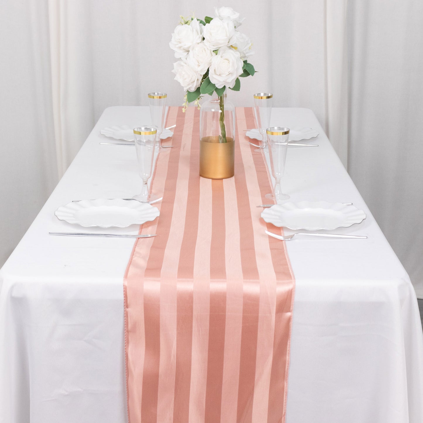 Dusty rose satin stripe table runner on a white table setting.