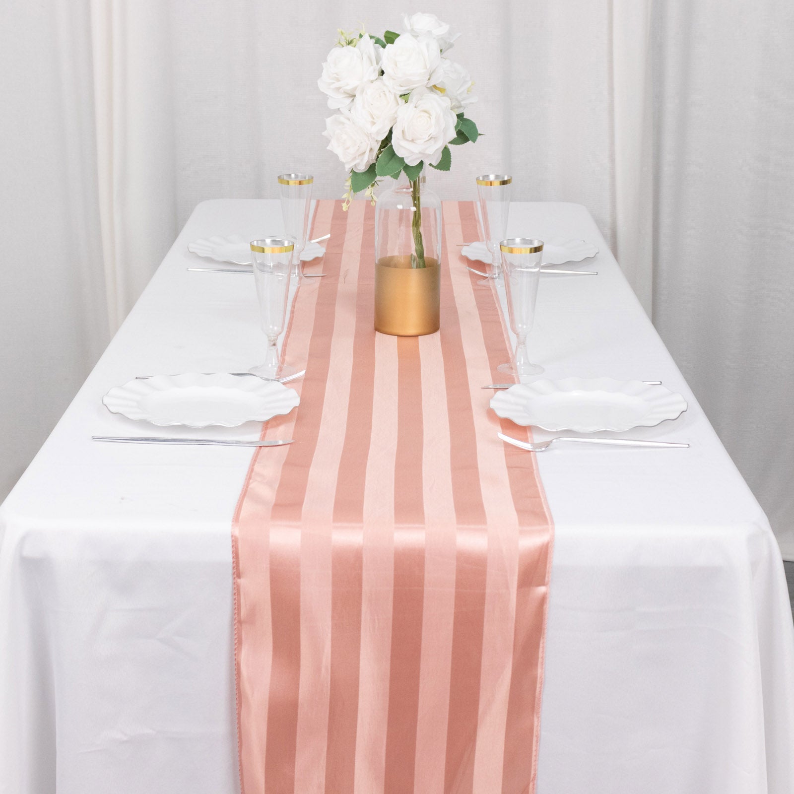 Dusty rose satin stripe table runner on a white table setting.