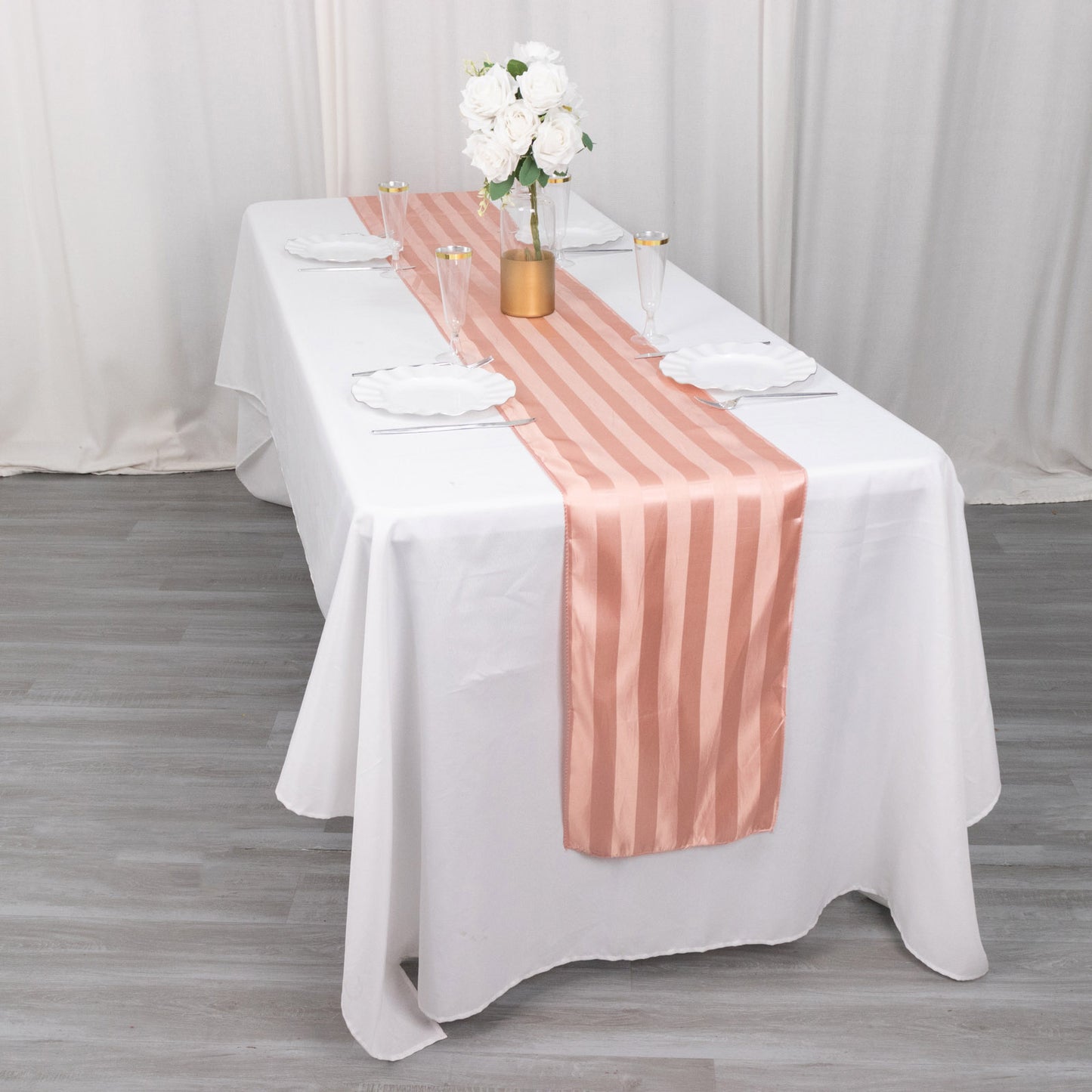 Dusty rose satin stripe table runner on a white tablecloth.