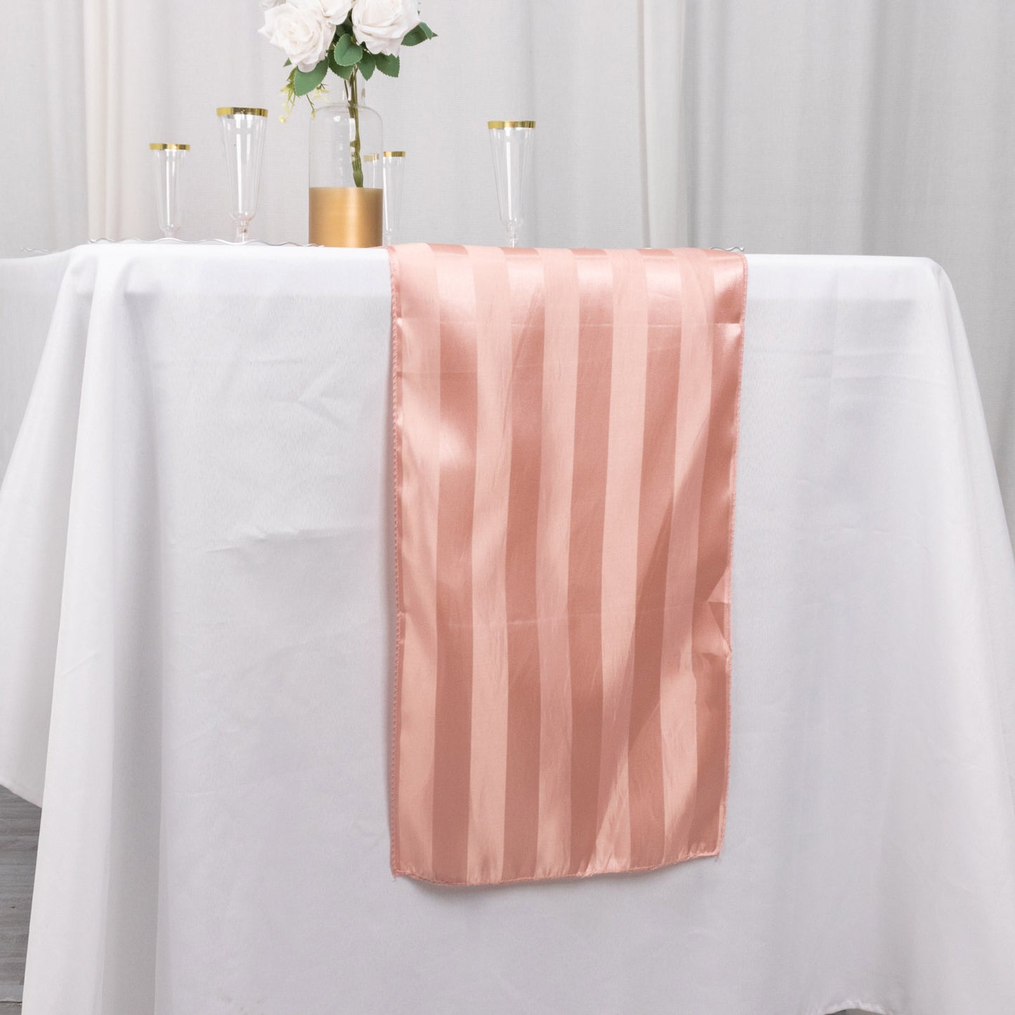 Dusty rose satin stripe table runner on a white table.