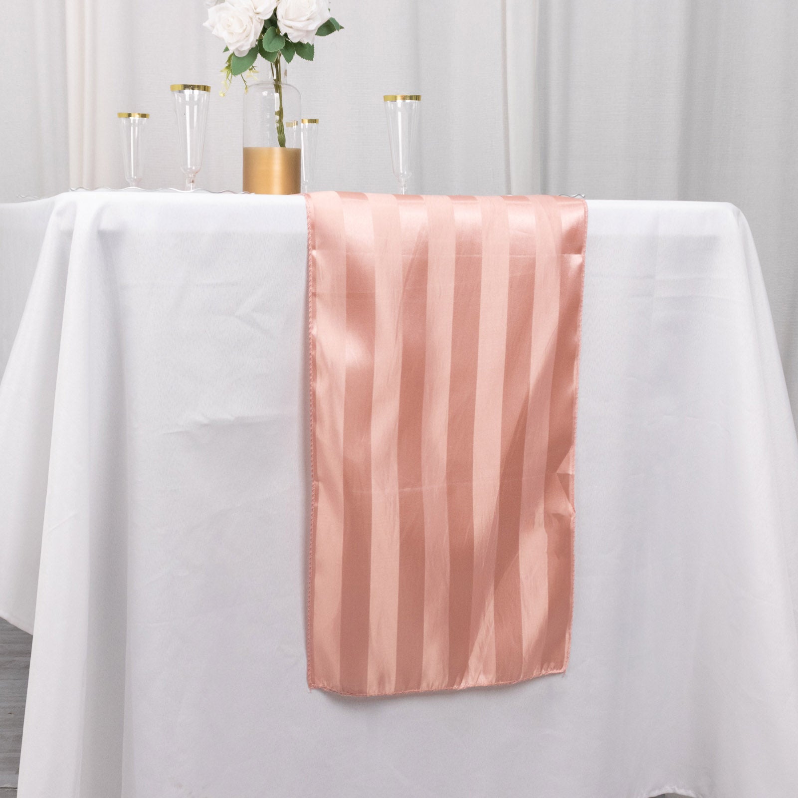 Dusty rose satin stripe table runner on a white table.