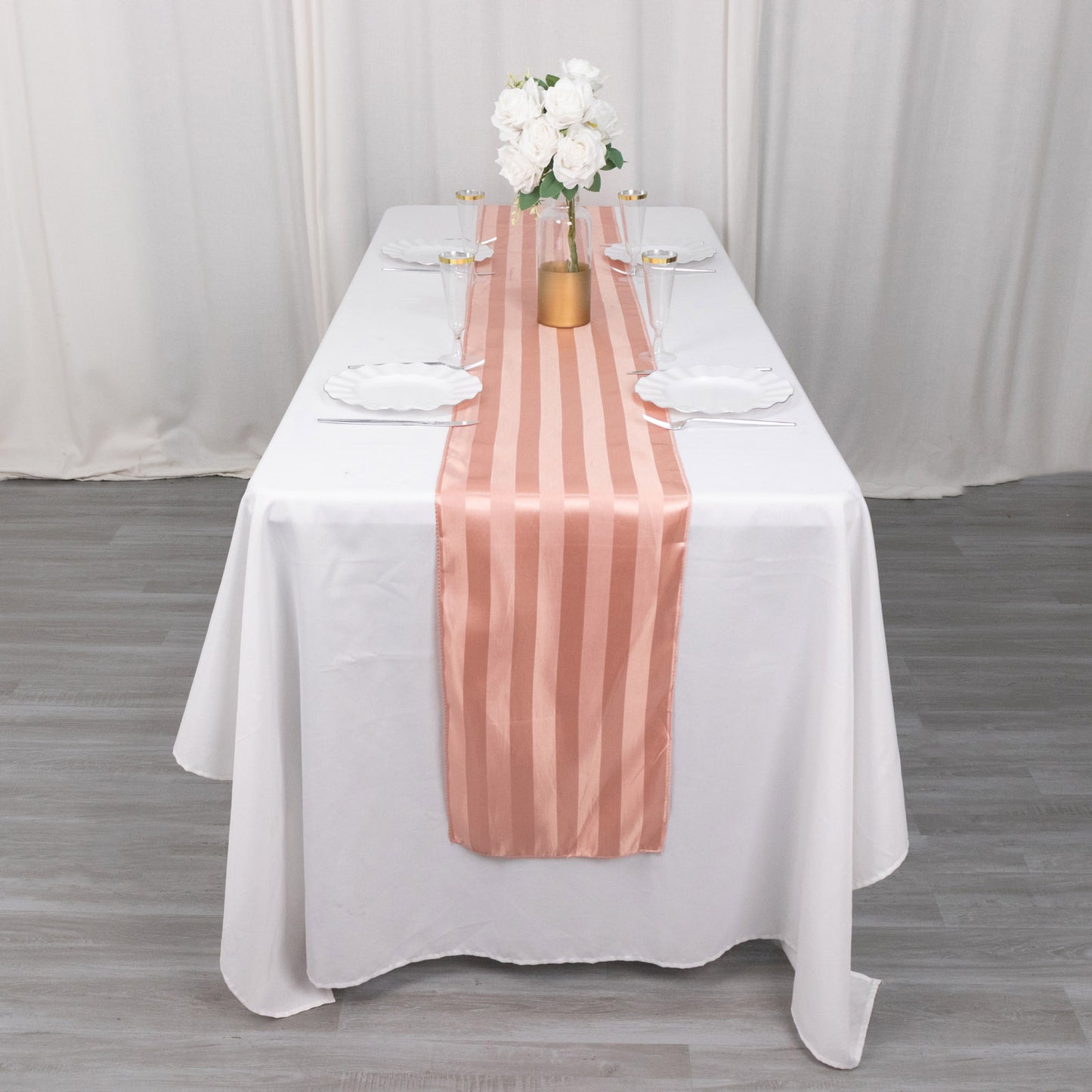 Dusty rose satin stripe table runner on a white table setting.