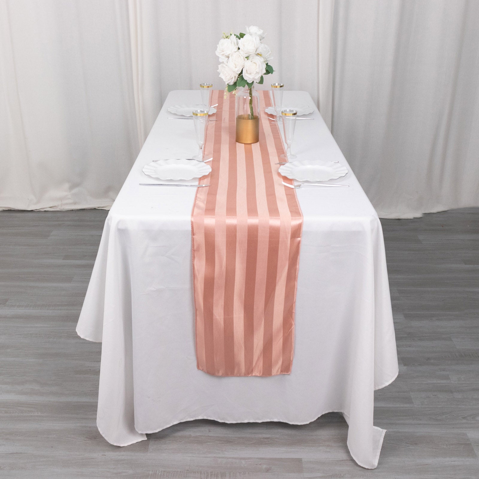 Dusty rose satin stripe table runner on a white table setting.