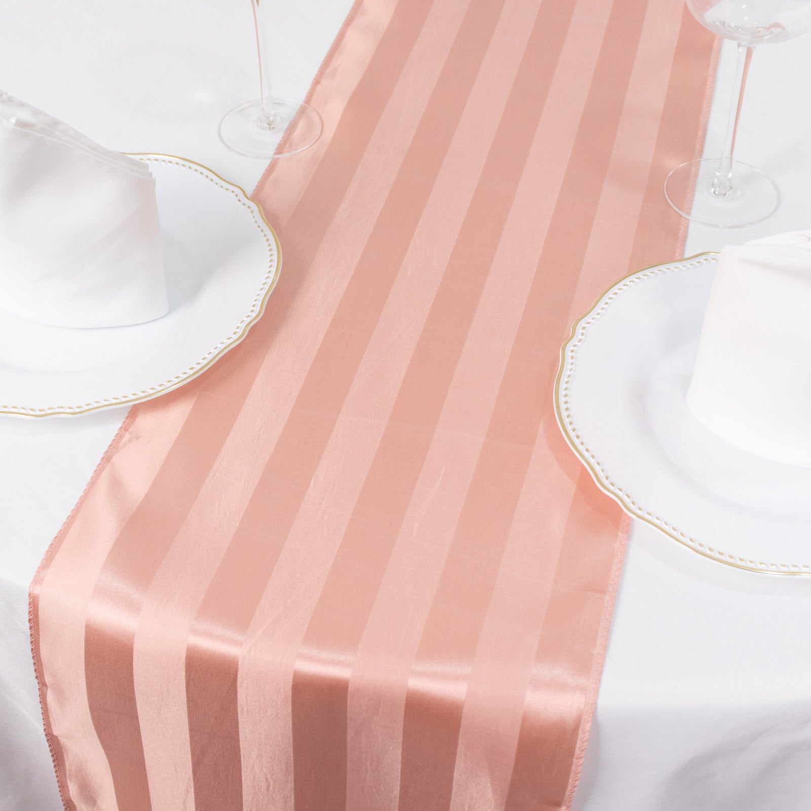 Dusty rose satin stripe table runner on a white table setting.