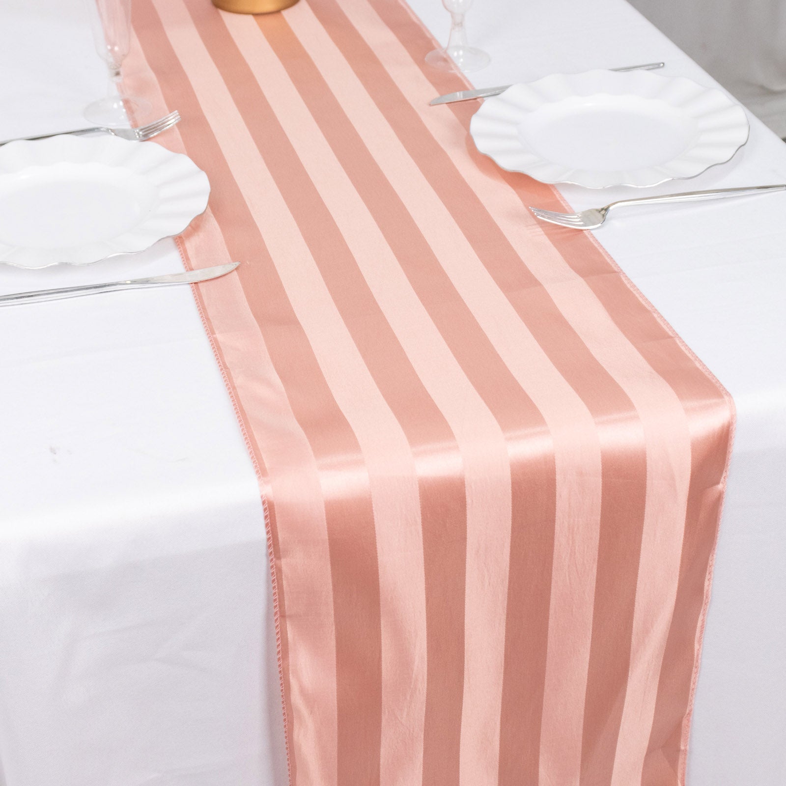Dusty rose satin stripe table runner on a white table setting.