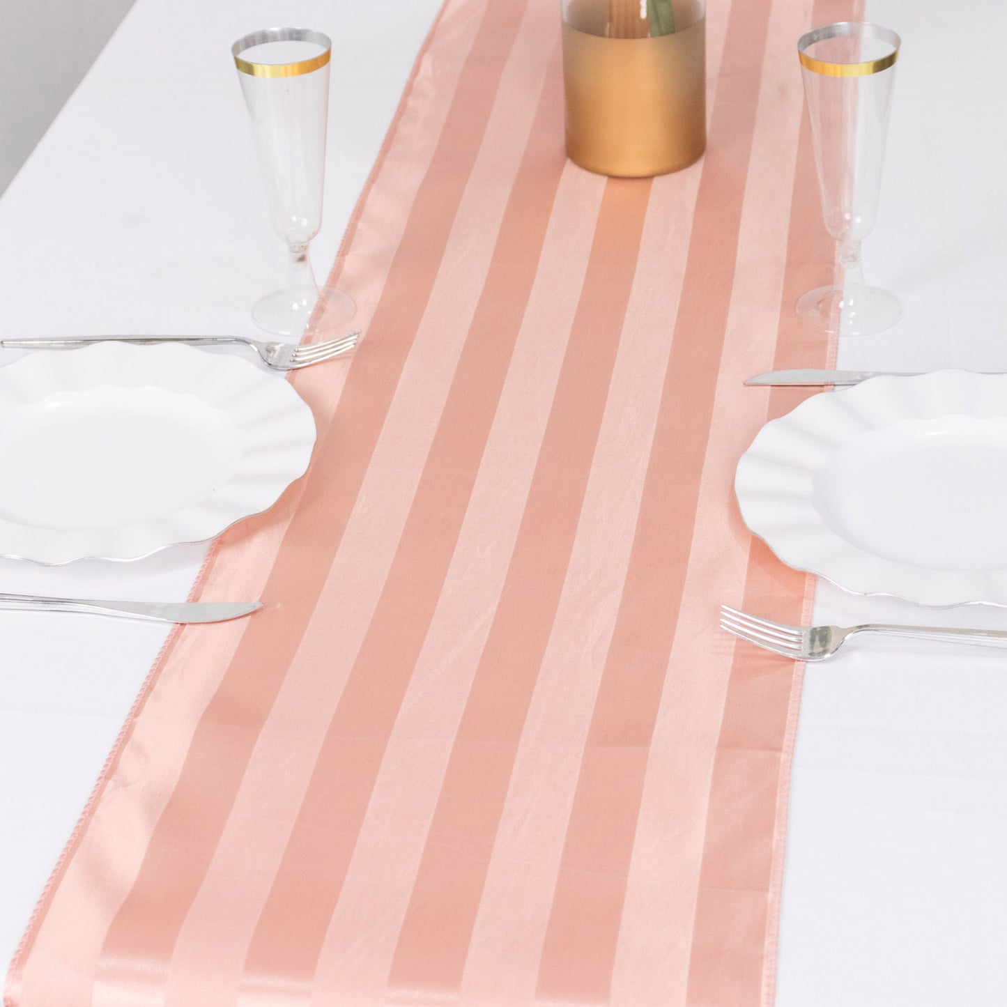 Dusty rose satin stripe table runner on a white table setting.