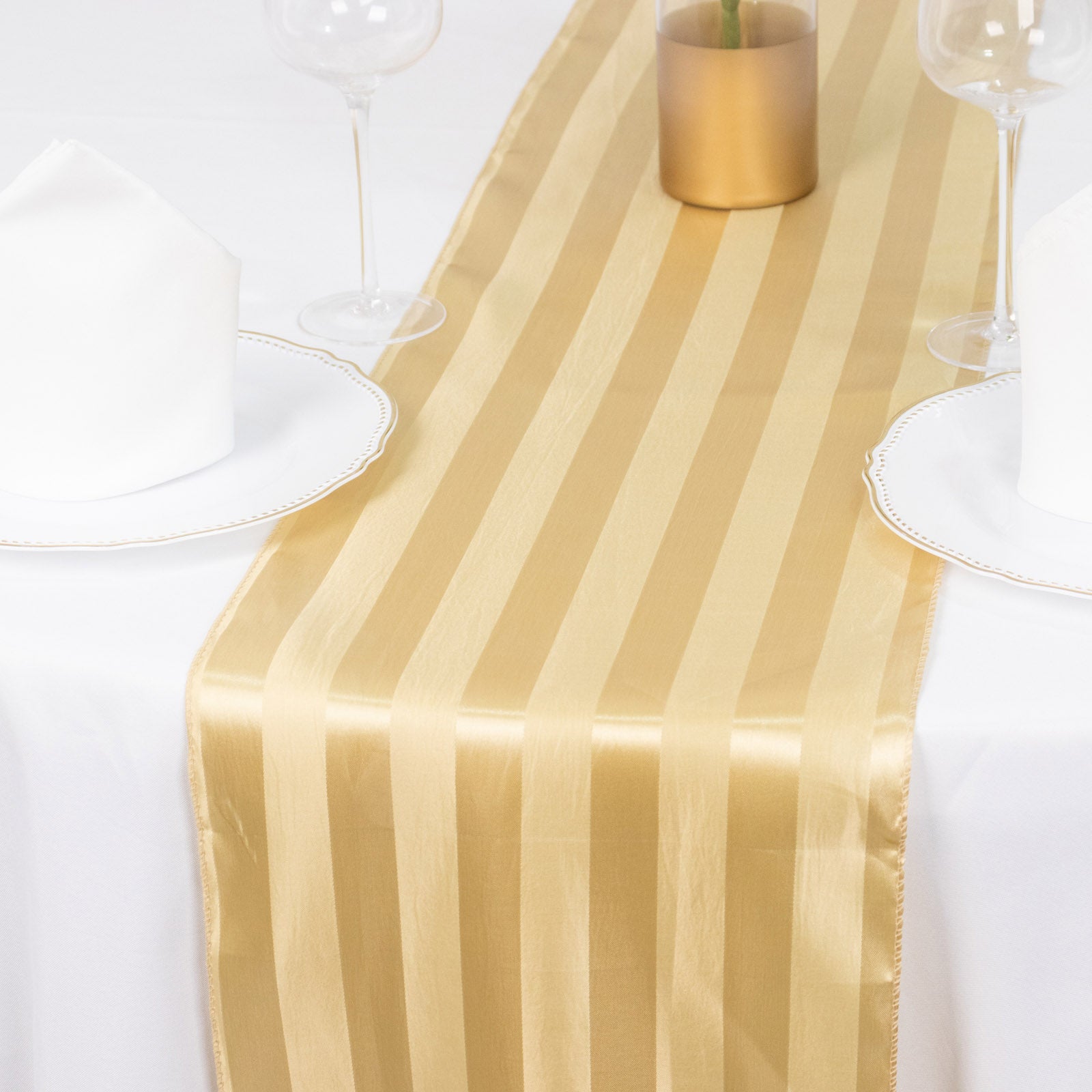 Champagne satin stripe table runner on a white table setting.