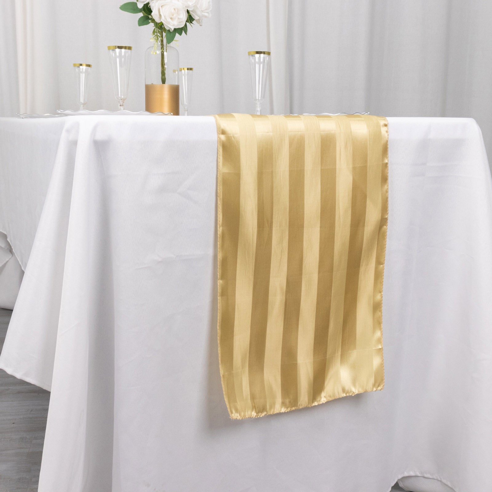 Champagne satin stripe table runner on a white table.