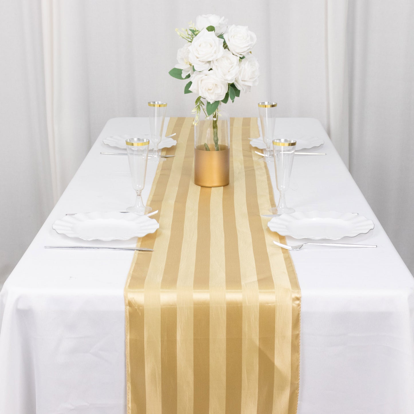 Champagne satin stripe table runner on a white table with floral centerpiece.