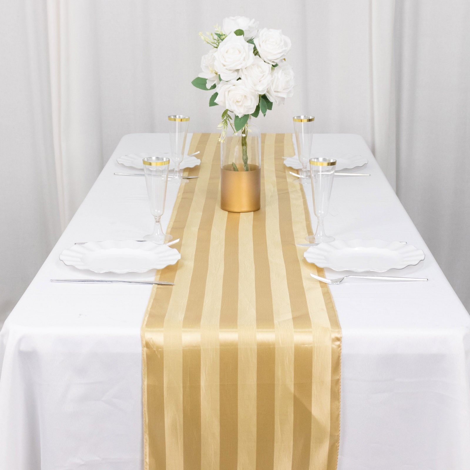 Champagne satin stripe table runner on a white table with floral centerpiece.