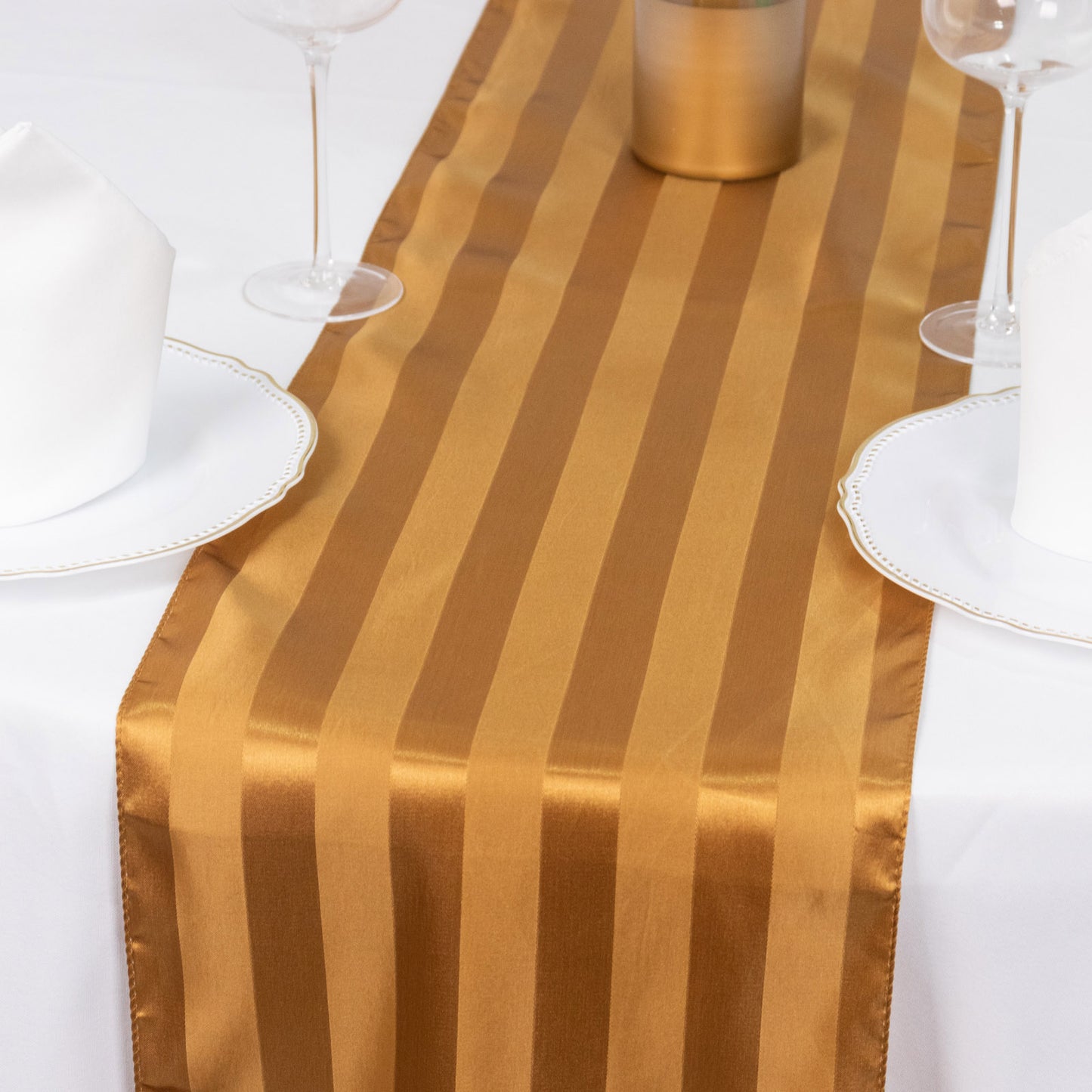 Gold satin stripe table runner on a white tablecloth.